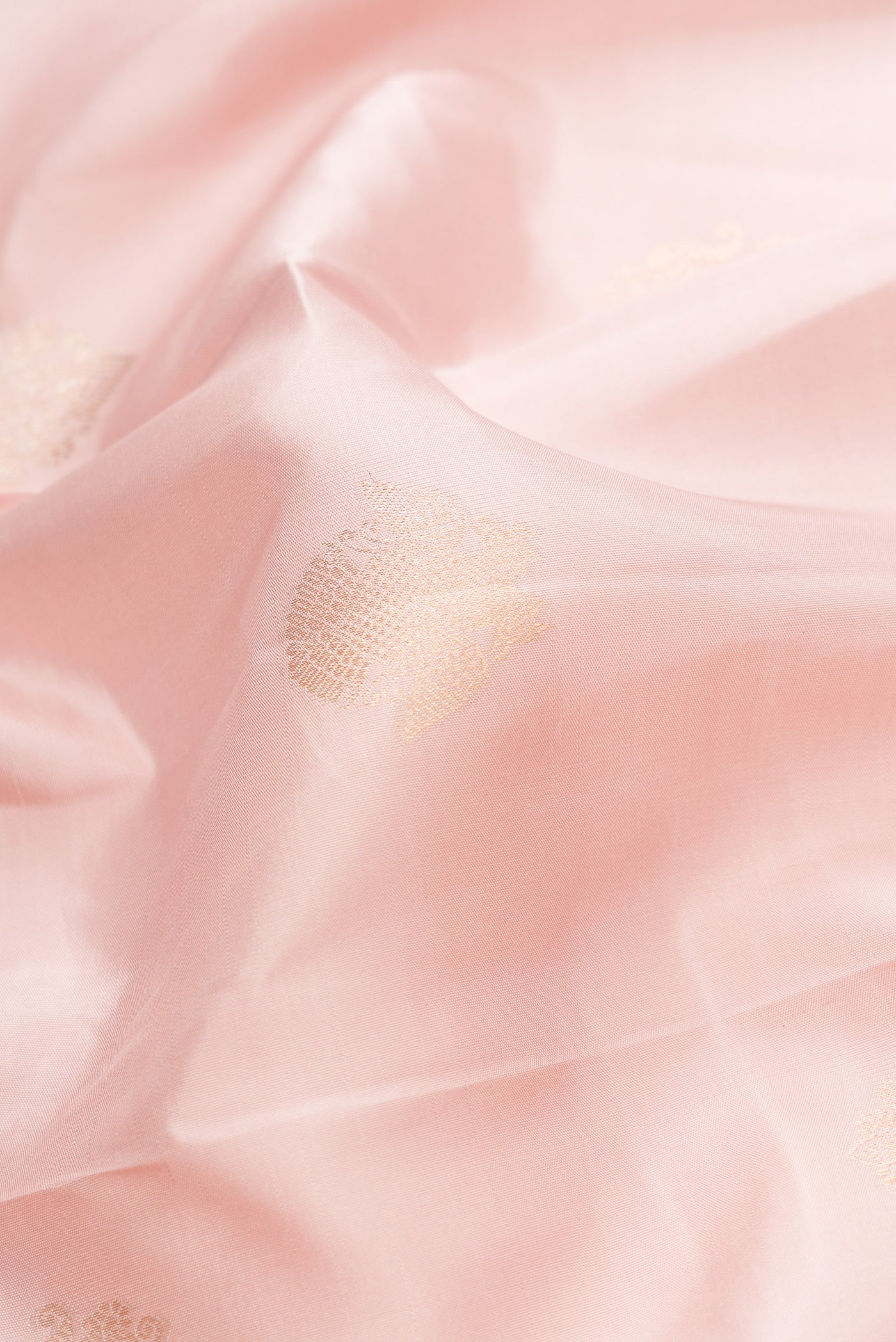 Close up of Rose Gold Dual Tone Kanchipuram Silk Saree with Zari Butta on the body and Zari Border.  displaying folds