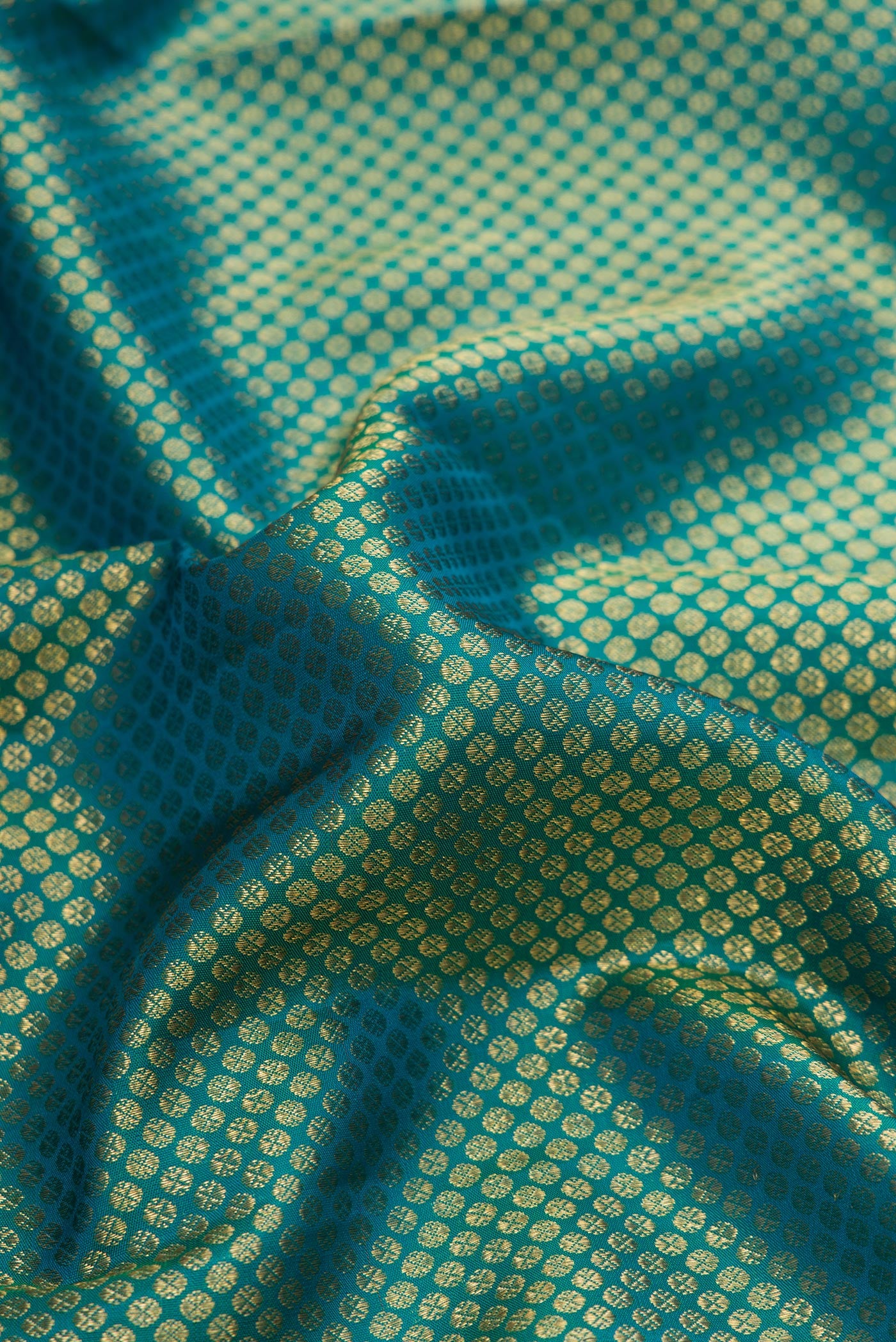 Close up of Green Dual Tone Kanjivaram Silk Saree with Zari Brocade on the body and Zari Border.  displaying folds