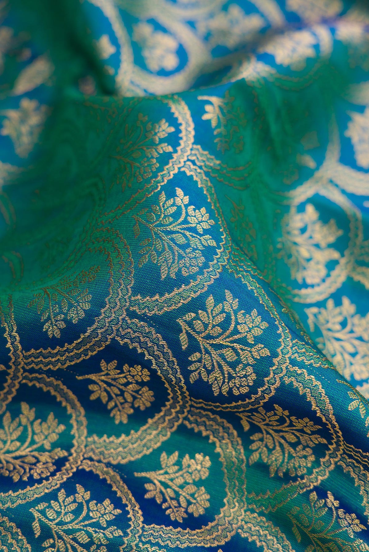 Close up of Peacock Blue Dual Tone Kanjivaram Silk Saree with Zari Brocade on the body and Zari Border.  displaying folds