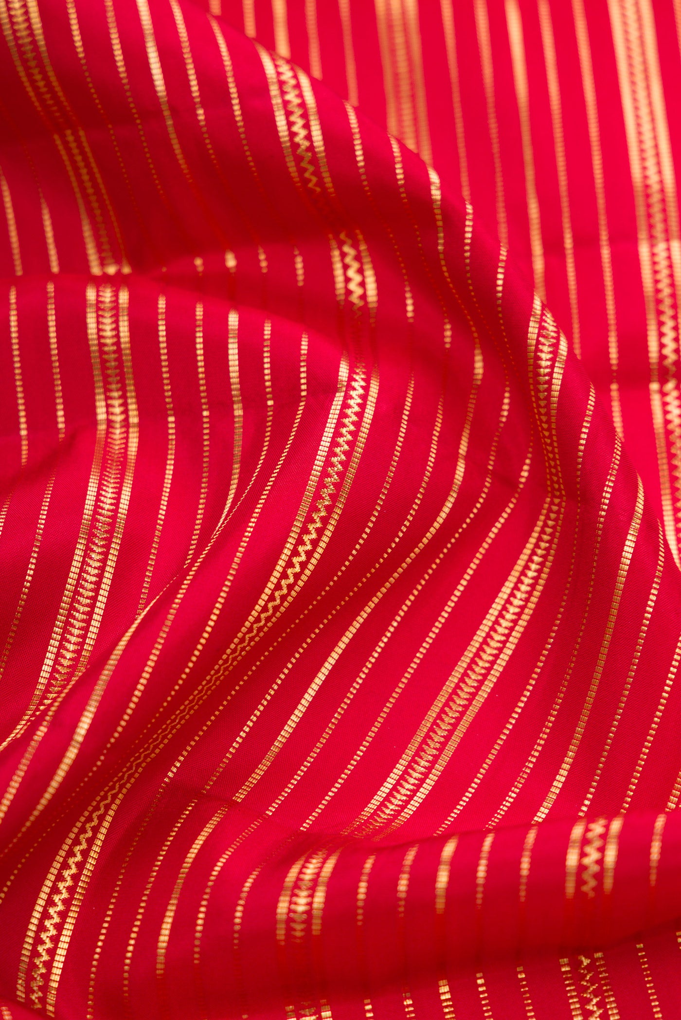 Close up of Red Dual Tone Kanjivaram Silk Saree with Stripes on the body and Zari Border.  displaying folds