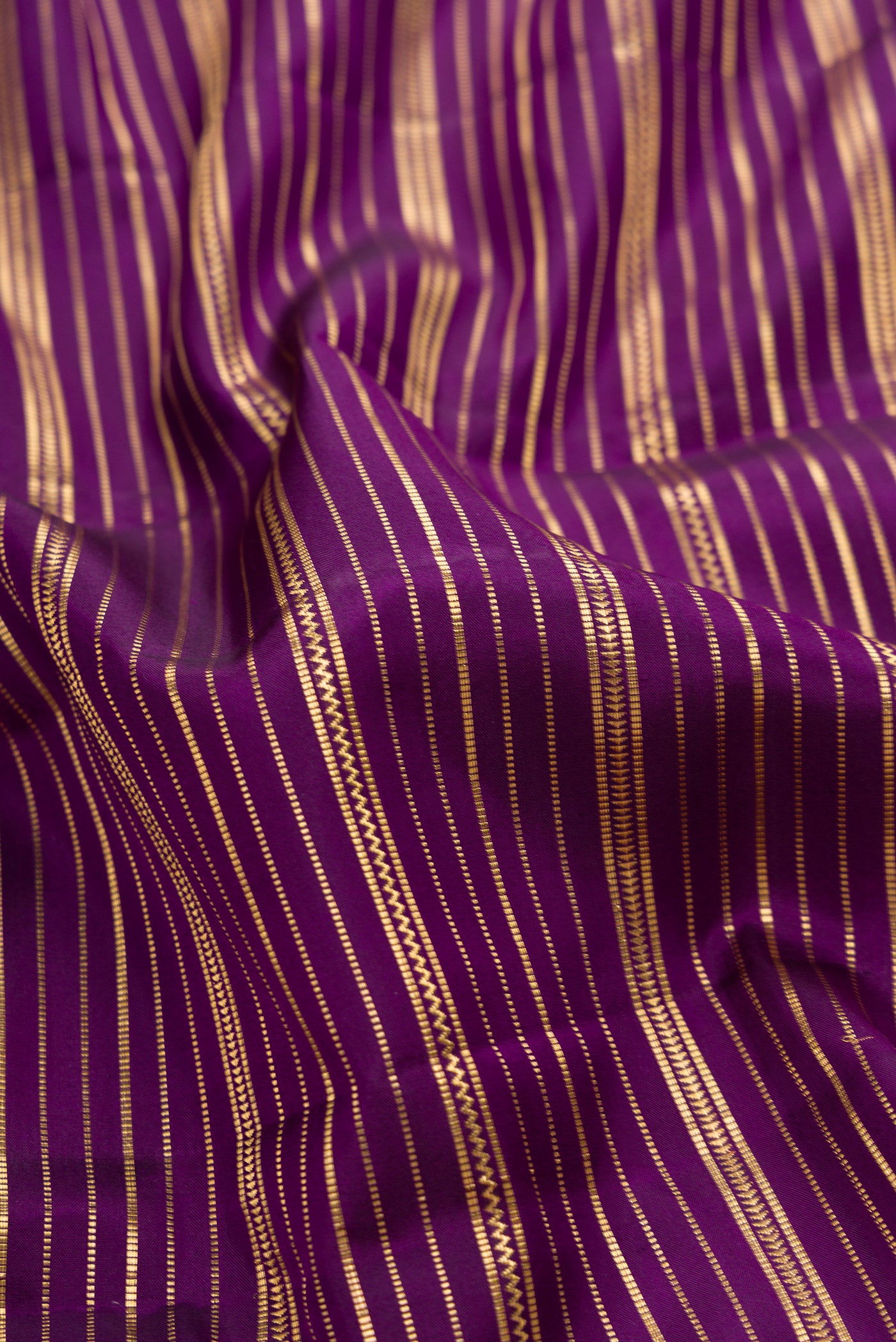 Close up of Violet Dual Tone Kanjivaram Silk Saree with Stripes on the body and Zari Border.  displaying folds