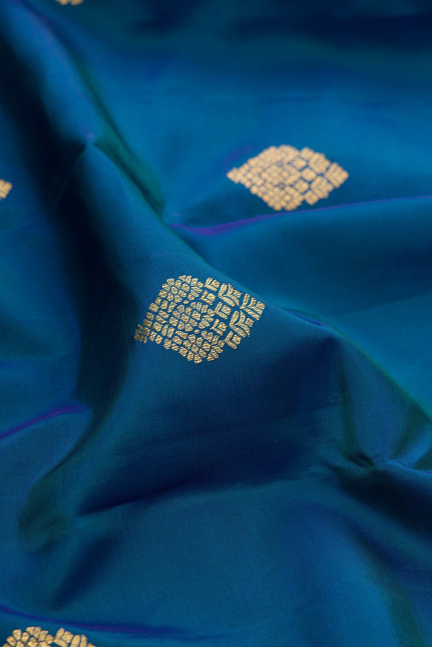 Close up of Peacock Blue Kanjivaram Silk Saree with Zari Butta on the body and Zari Border.  displaying folds
