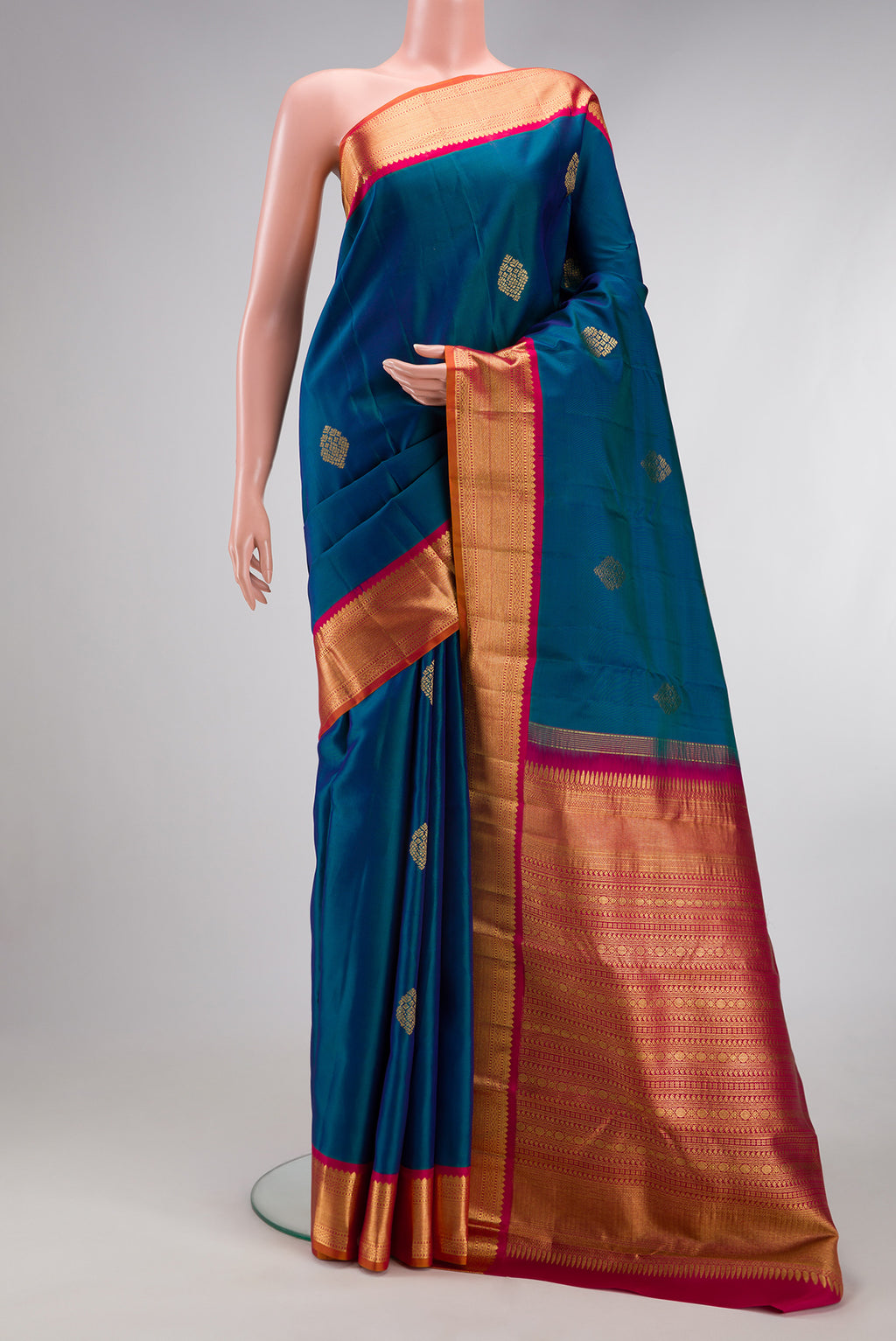 Peacock Blue Kanjivaram Silk Saree with Zari Butta on the body and Zari Border.  displayed on a mannequin