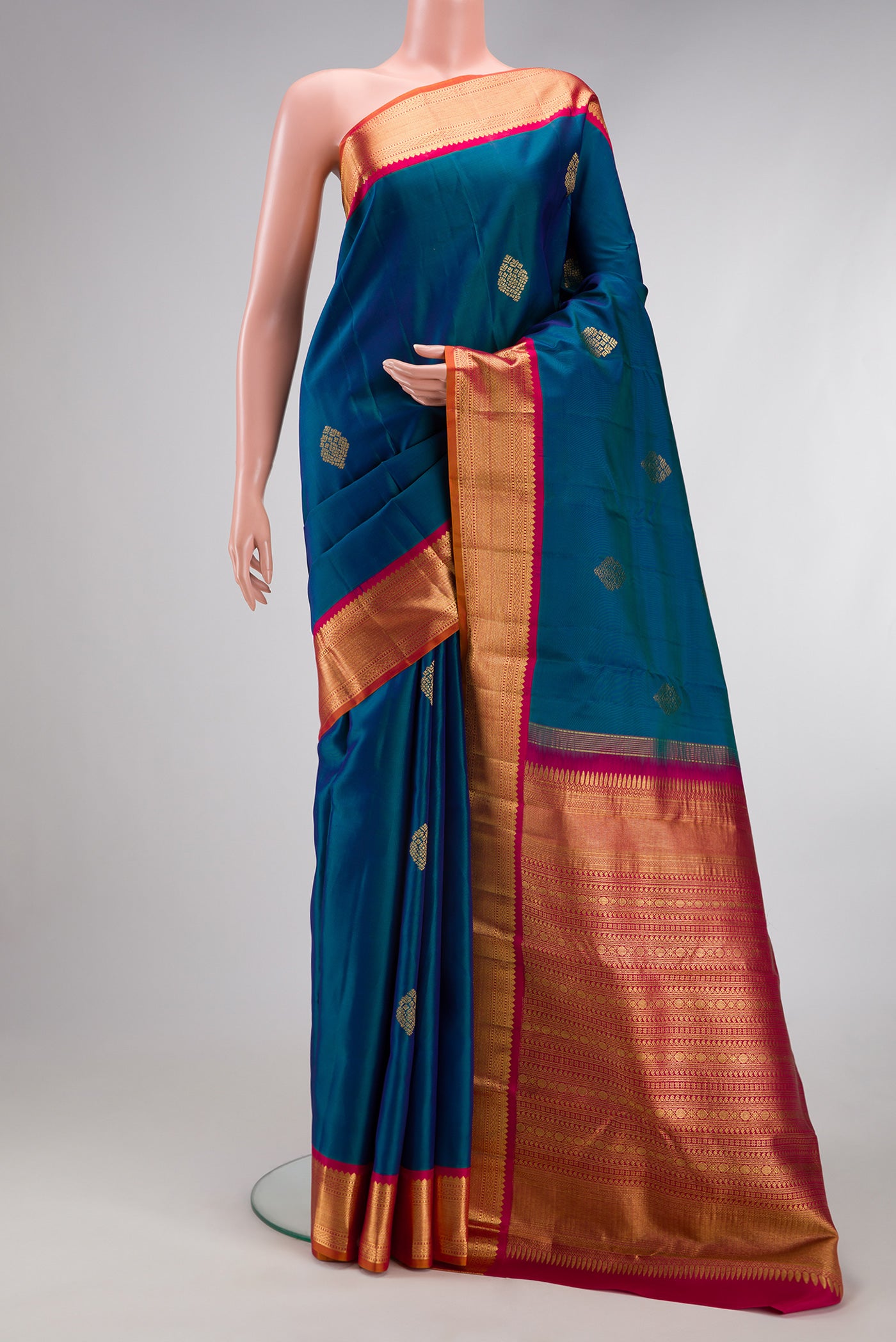 Peacock Blue Kanjivaram Silk Saree with Zari Butta on the body and Zari Border.  displayed on a mannequin