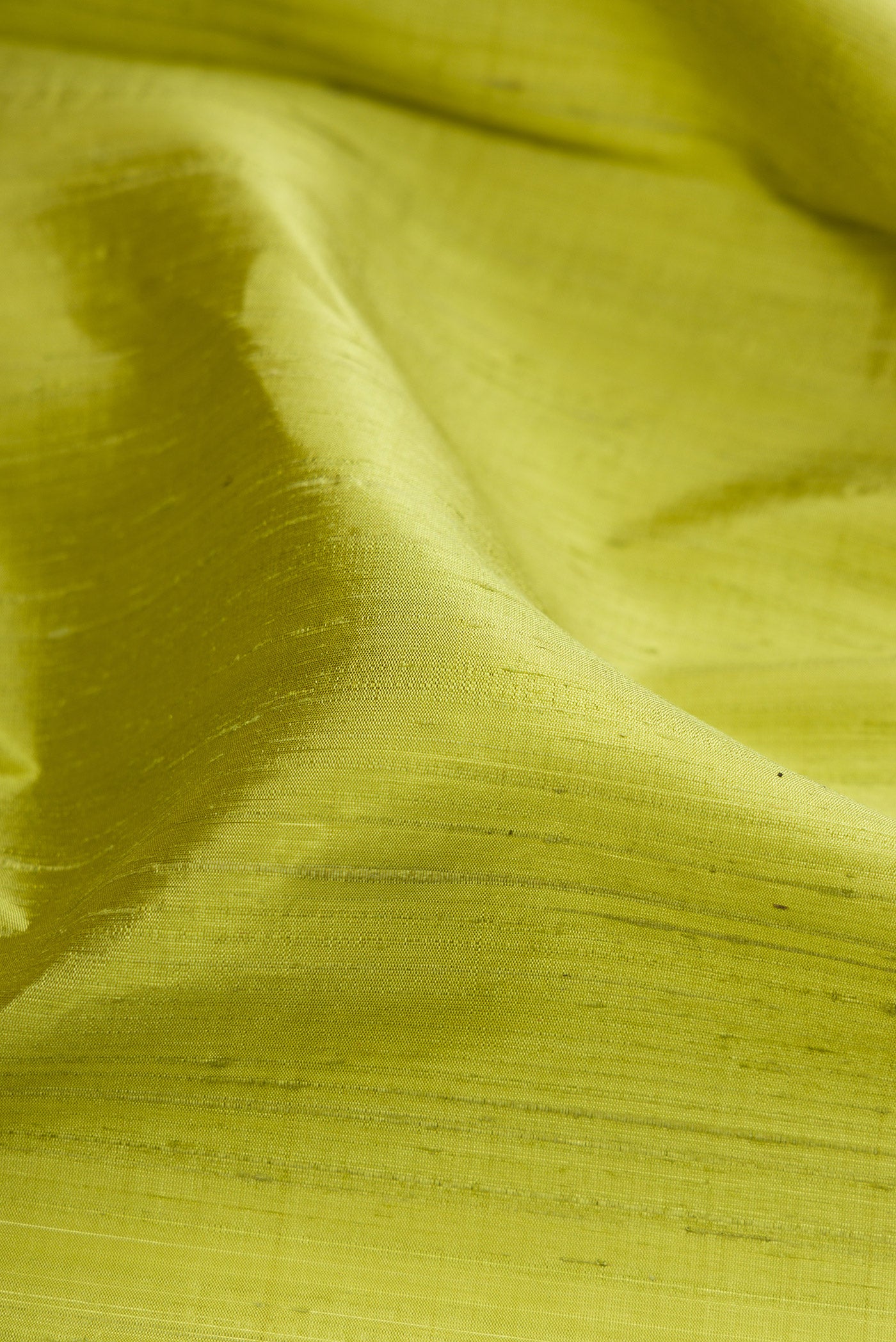 Close up of Pista Green Raw Silk Saree with Plain Body and Zari Border.  displaying folds