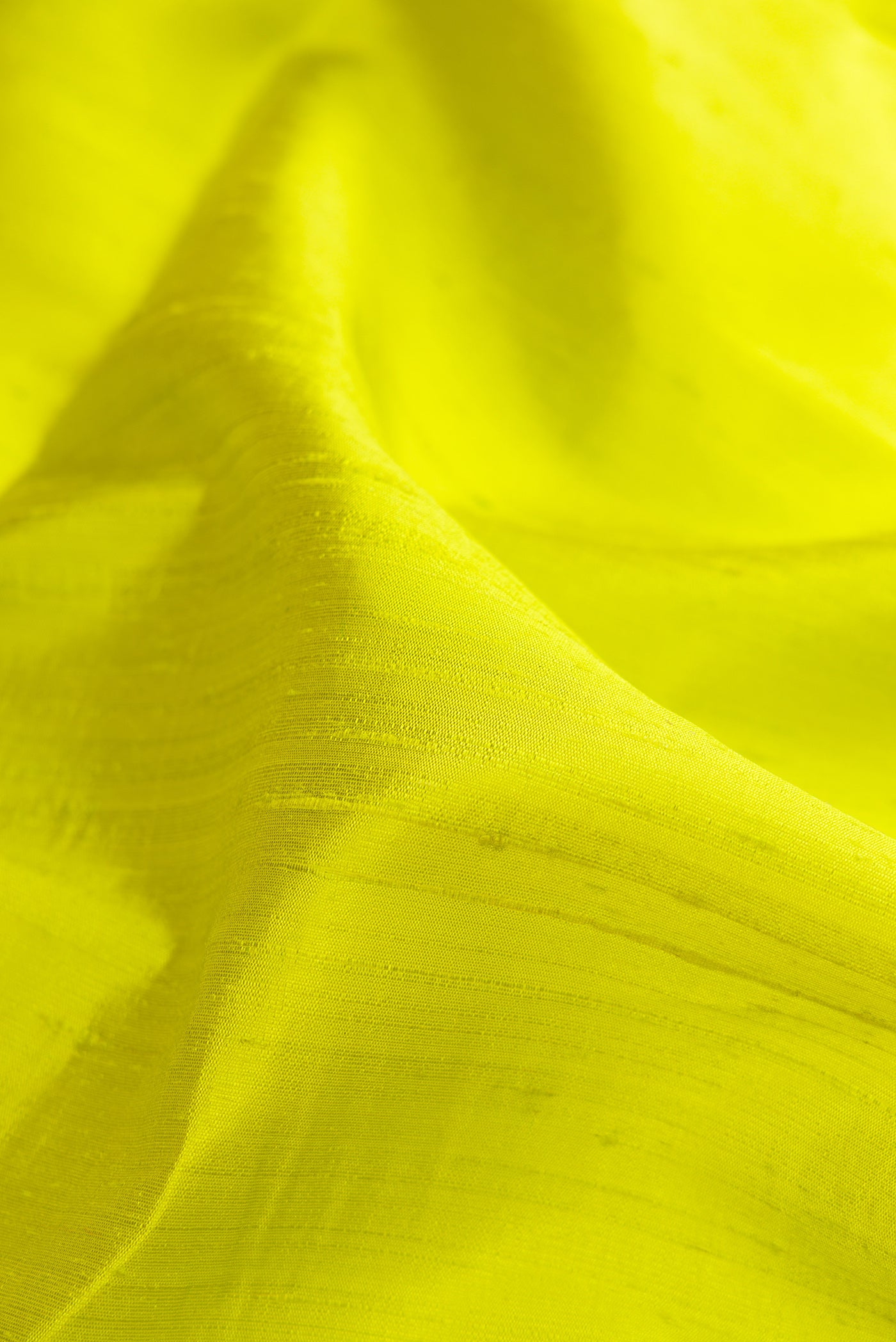 Close up of Parrot Green Raw Silk Saree with Plain Body and Zari Border.  displaying folds