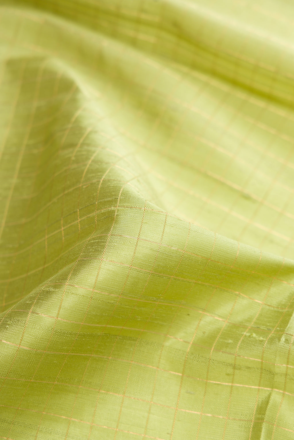 Close up of Pista Green Raw Silk Saree with Checked design on the body and Zari Border.  displaying folds