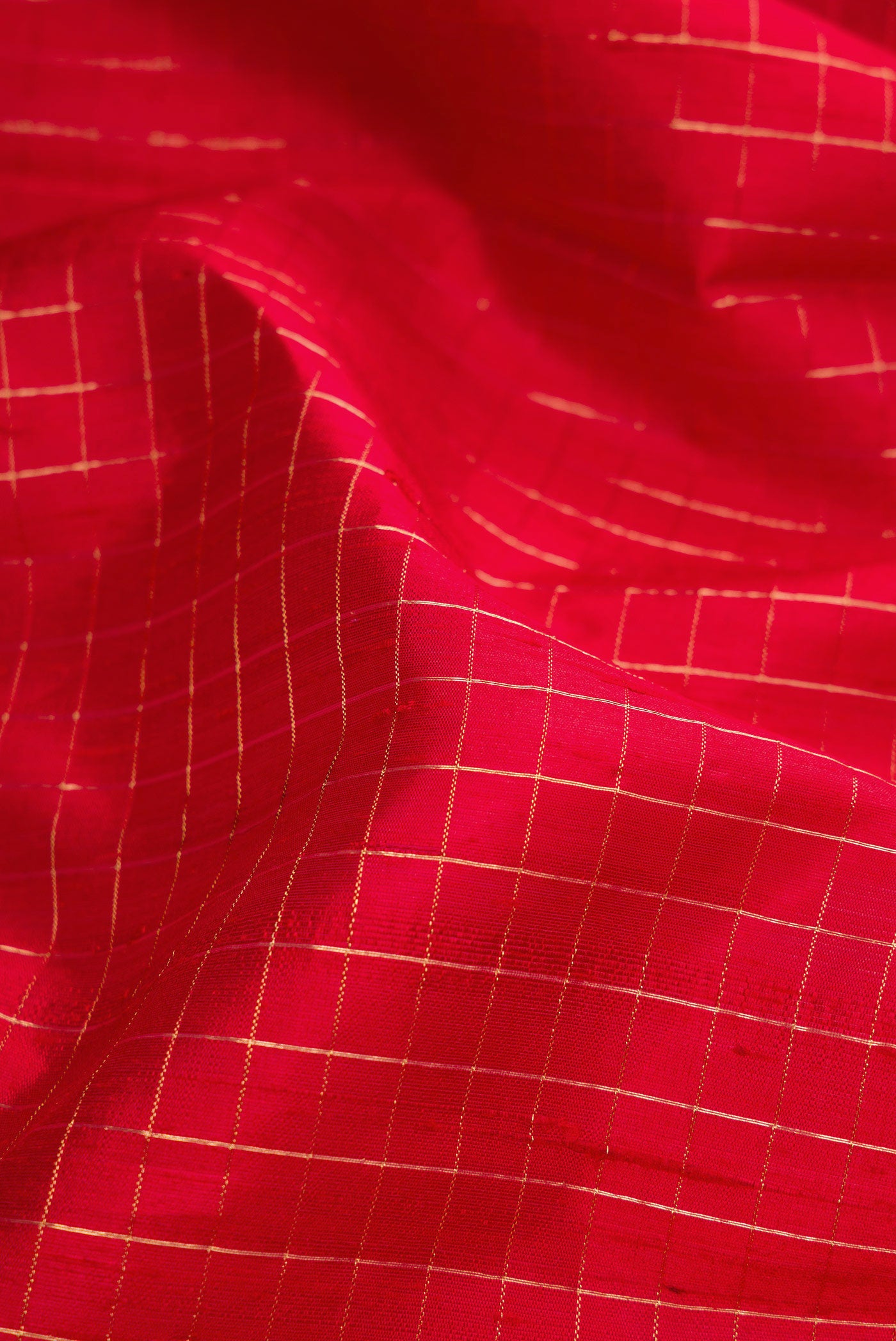 Close up of Red Raw Silk Saree with Checked design on the body and Zari Border.  displaying folds
