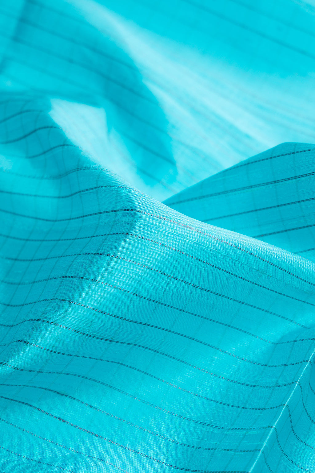 Close up of Sky Blue Raw Silk Saree with Checked design on the body and Zari Border.  displaying folds
