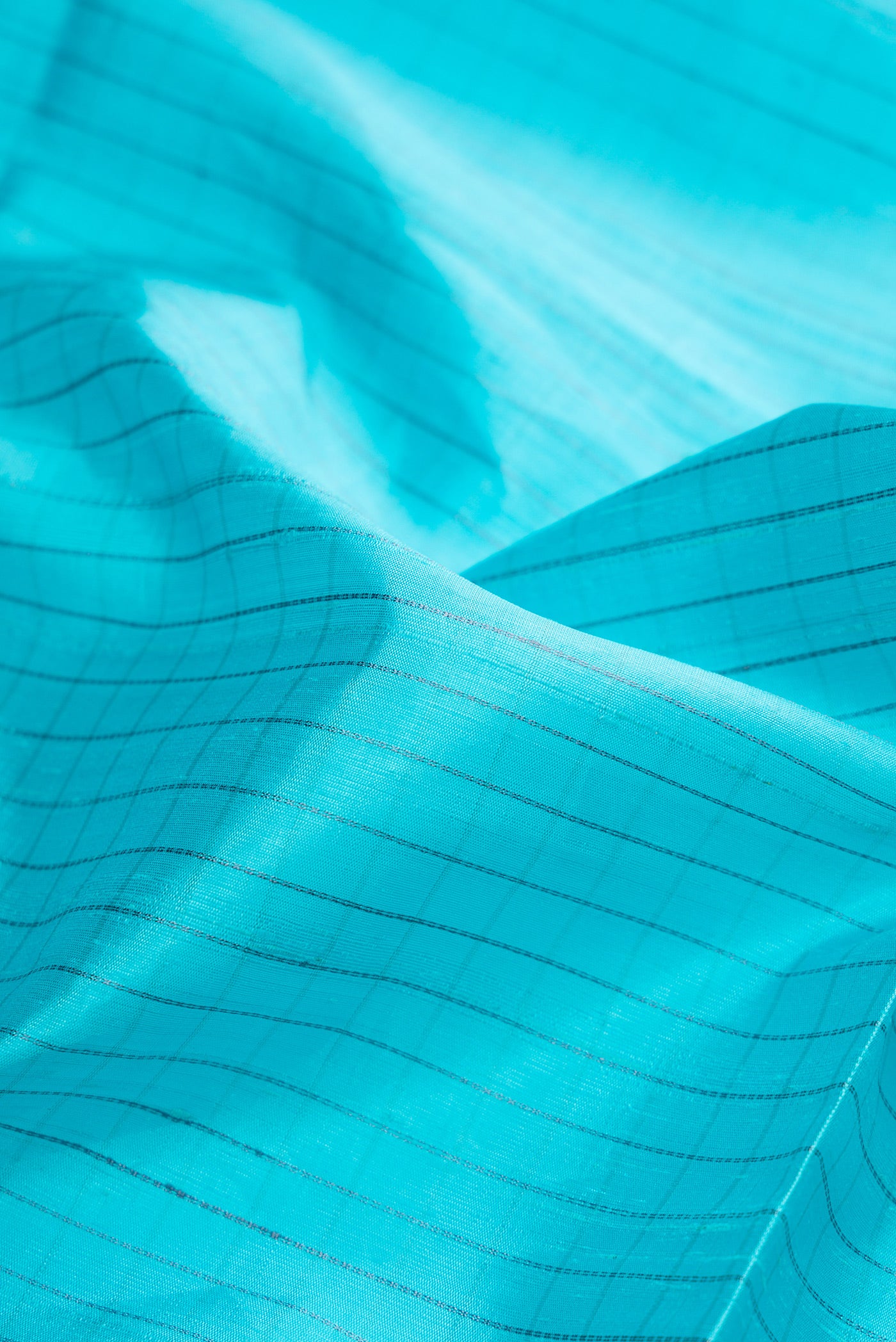 Close up of Sky Blue Raw Silk Saree with Checked design on the body and Zari Border.  displaying folds