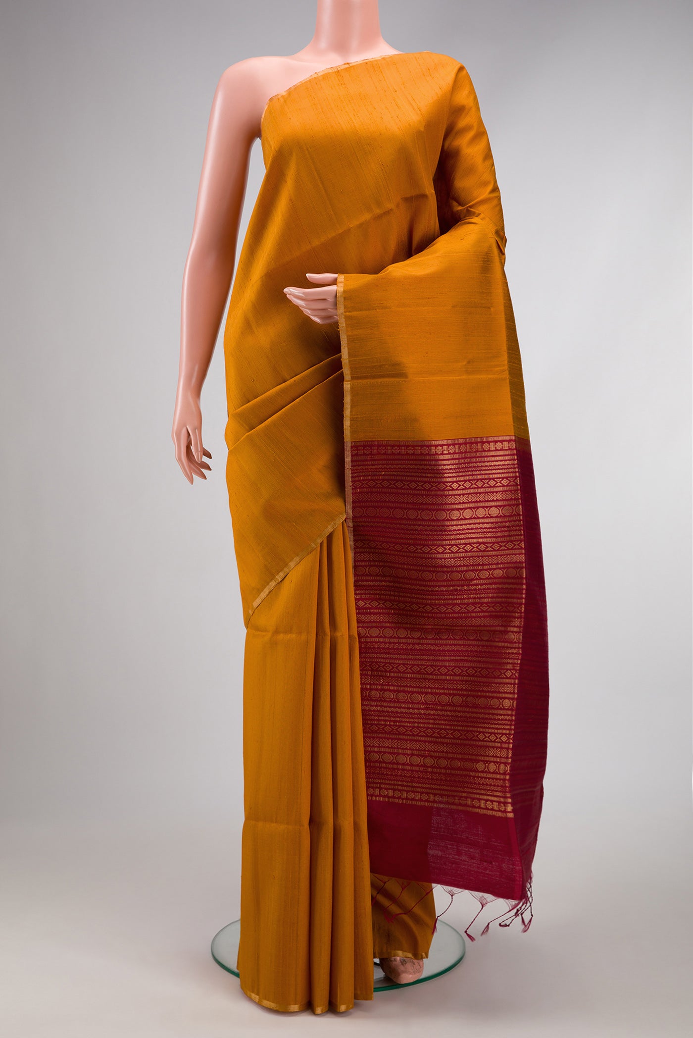 Mustard Raw Silk Saree with Plain Body and Zari Border.  displayed on a mannequin