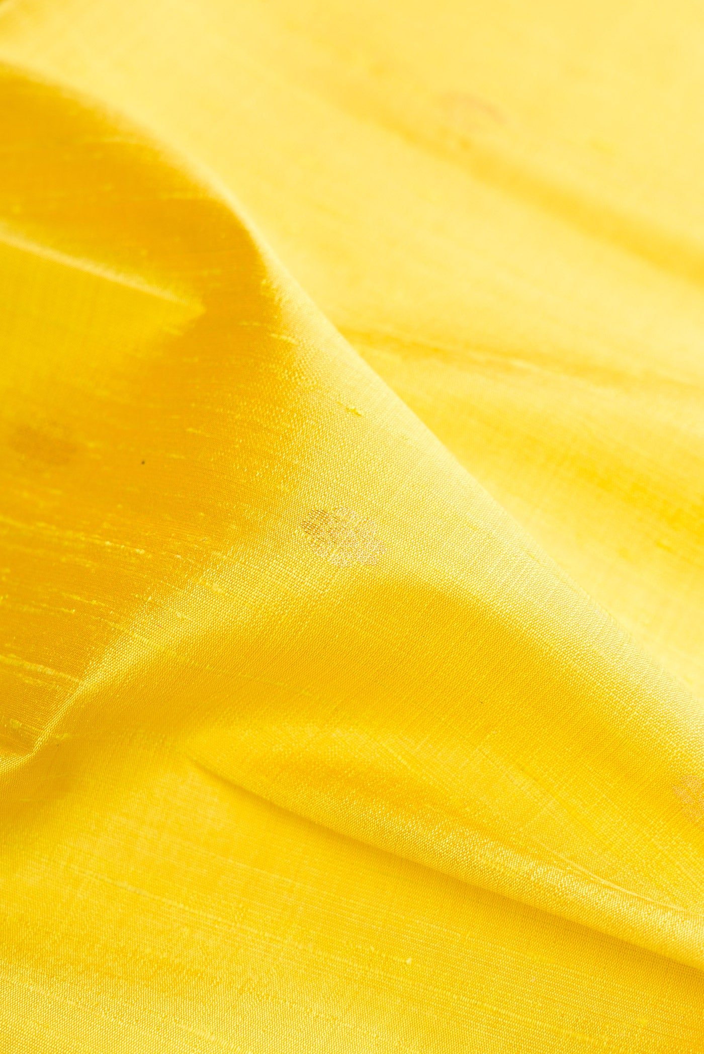 Close up of Lemon Yellow Dual Tone Raw Silk Saree with Zari Butta on the body and Zari Border.  displaying folds