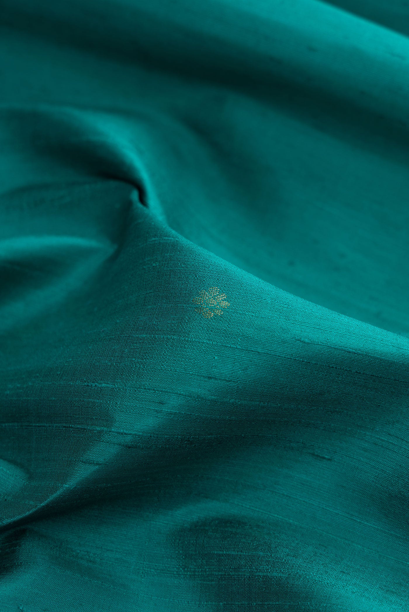 Close up of Peacock Blue Dual Tone Raw Silk Saree with Zari Butta on the body and Fancy Border.  displaying folds