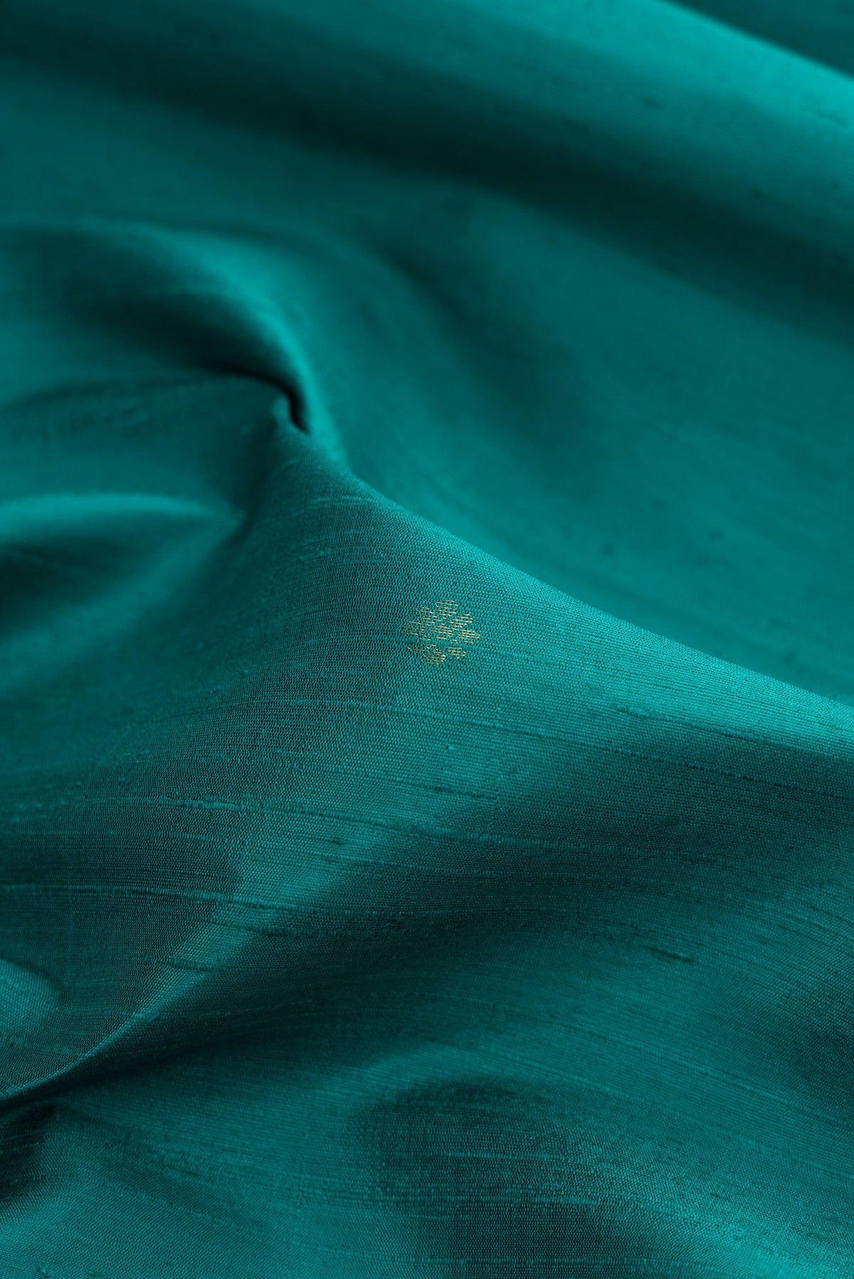 Close up of Peacock Blue Dual Tone Raw Silk Saree with Zari Butta on the body and Fancy Border.  displaying folds