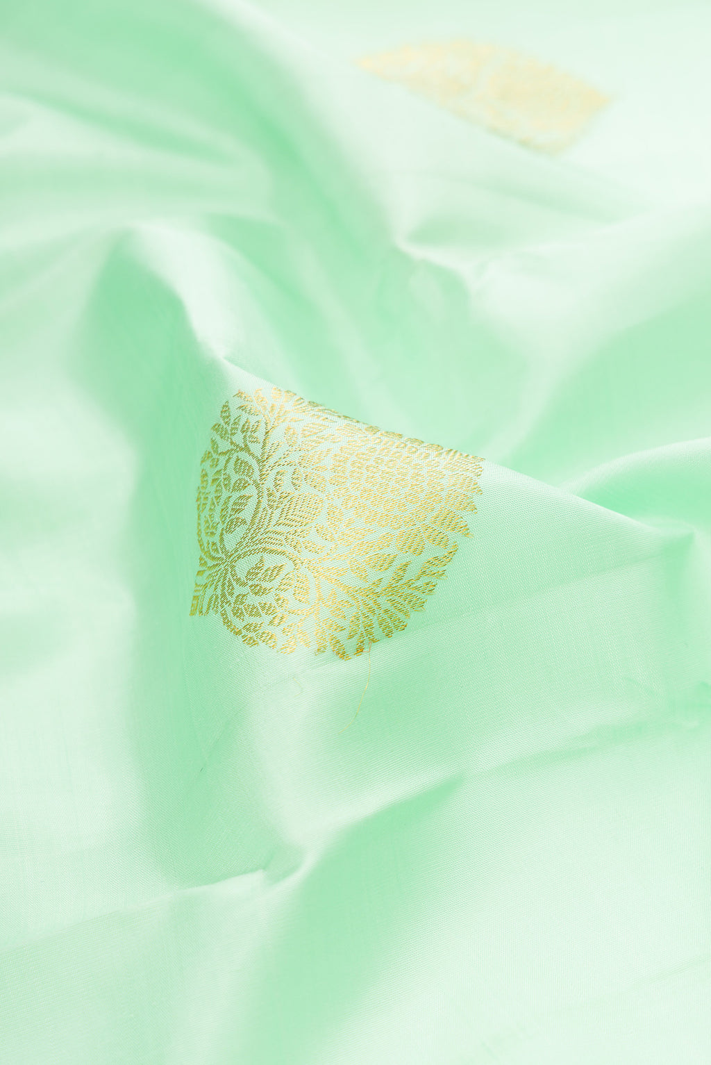 Close up of Pista Green Kanjivaram Silk Saree with Zari Butta on the body and Zari Border.  displaying folds