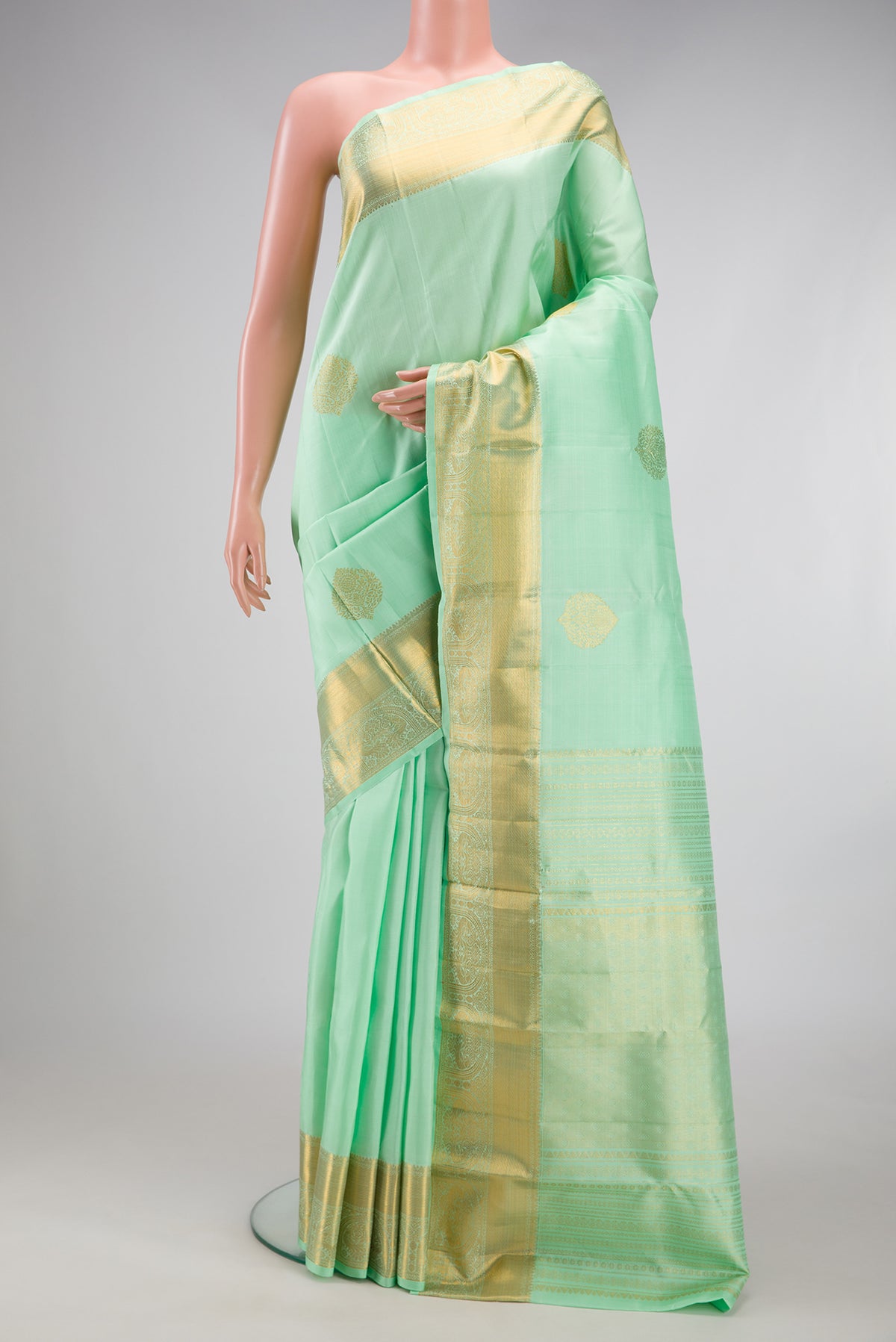 Pista Green Kanjivaram Silk Saree with Zari Butta on the body and Zari Border.  displayed on a mannequin