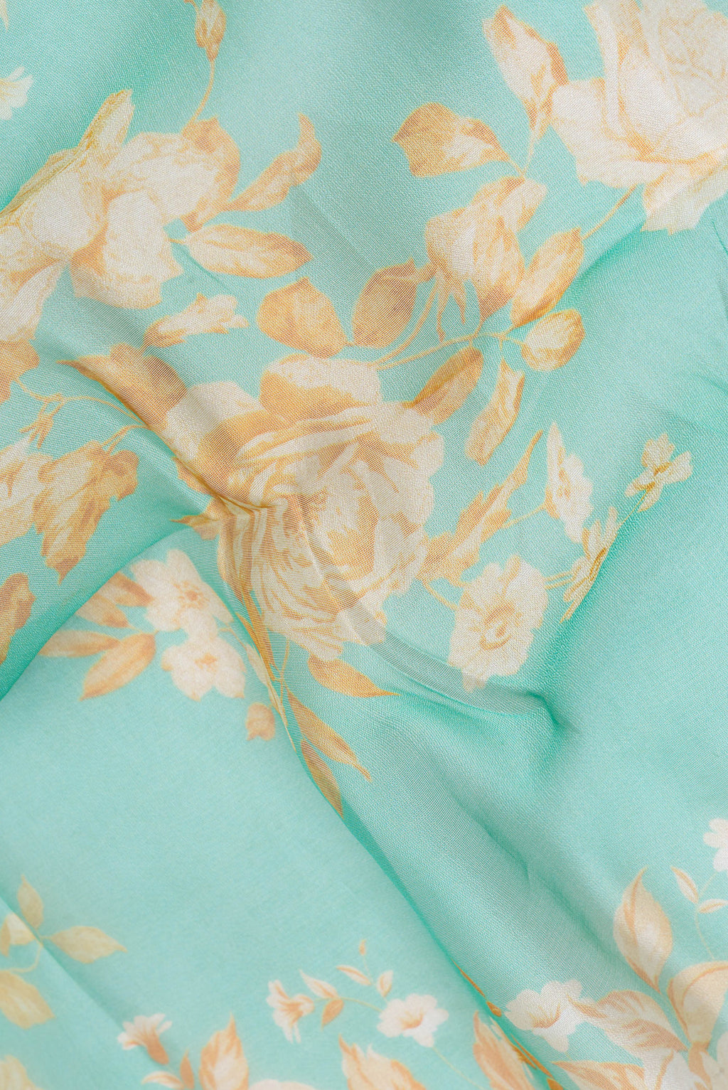 Close up of Sea Green Organza Silk Saree with Floral Print on the body and Zari Border.  displaying folds