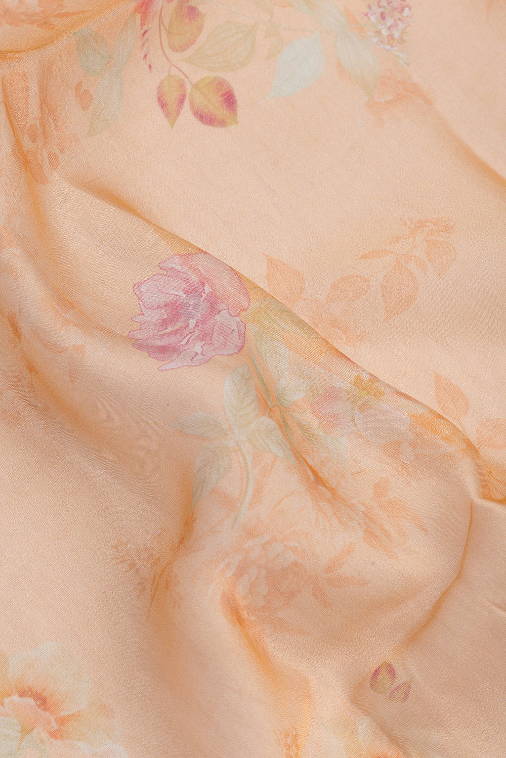 Close up of Golden Peach Organza Silk Saree with Floral Print on the body and Zari Border.  displaying folds