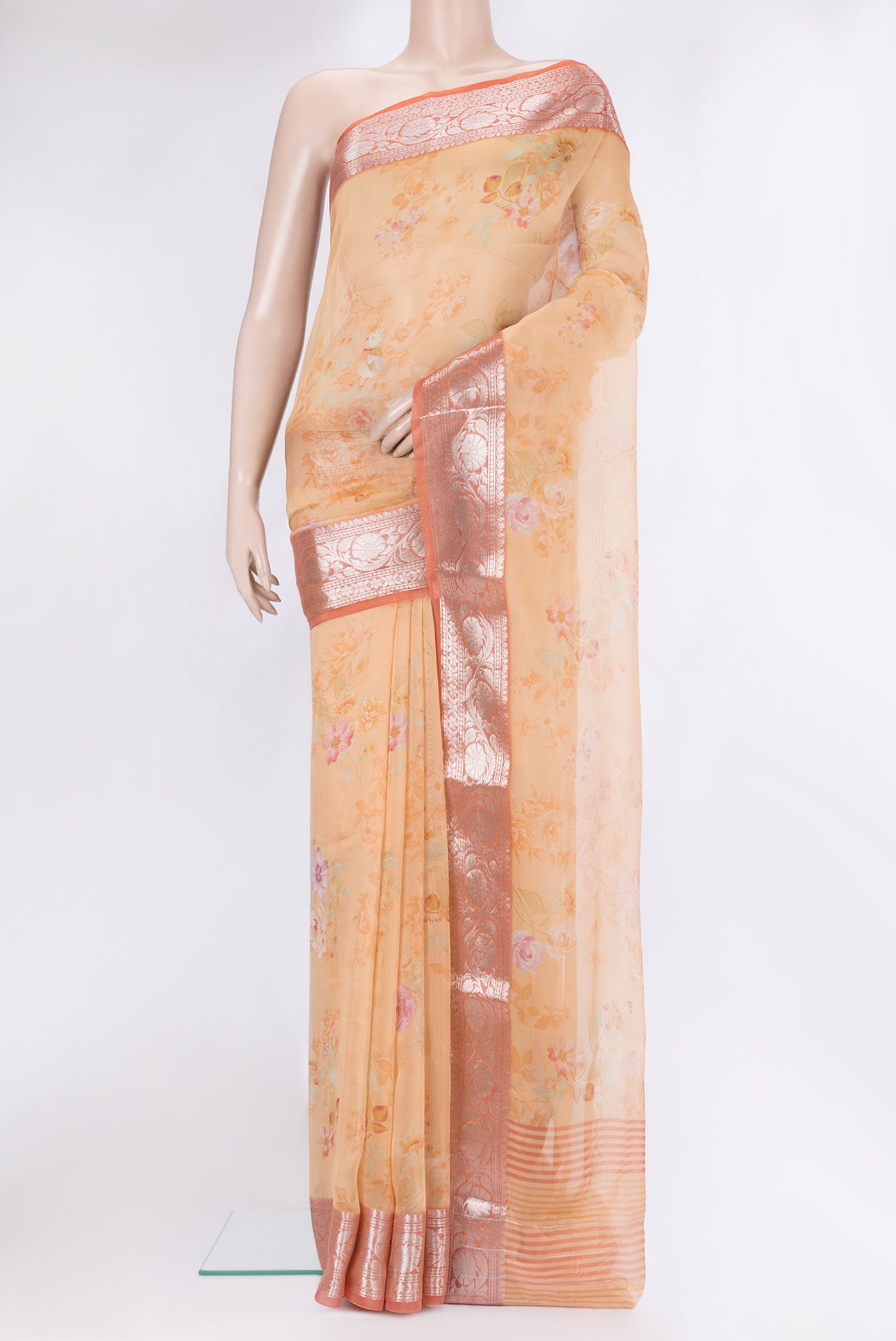 Golden Peach Organza Silk Saree with Floral Print on the body and Zari Border.  displayed on a mannequin