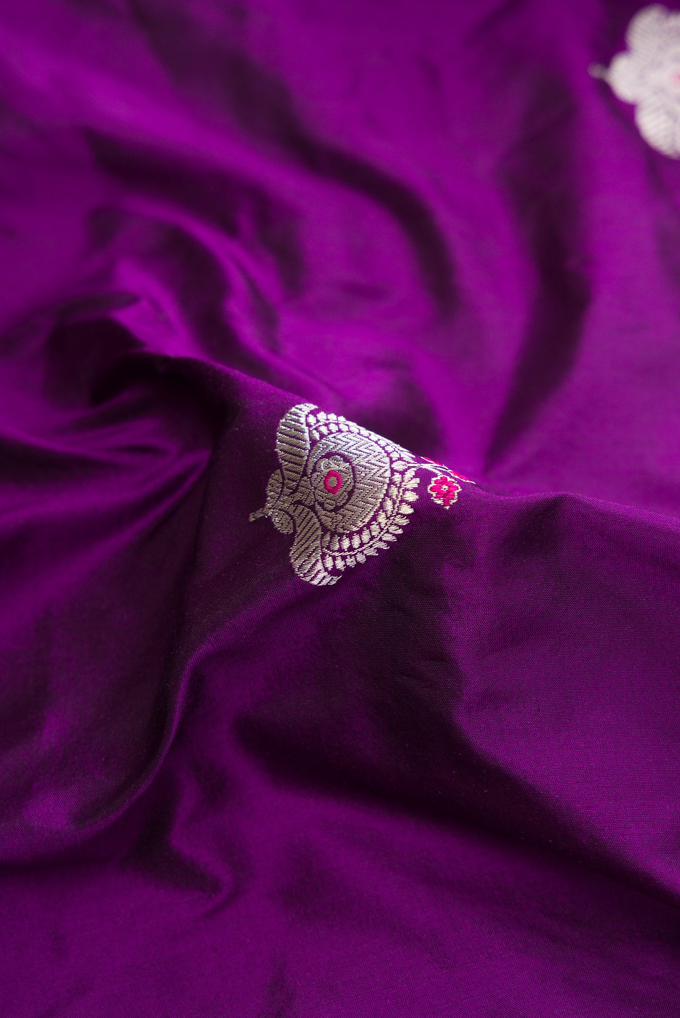 Close up of Violet Dual Tone Banarasi Silk Saree with Zari And Thread Butta on the body and Fancy Border.  displaying folds