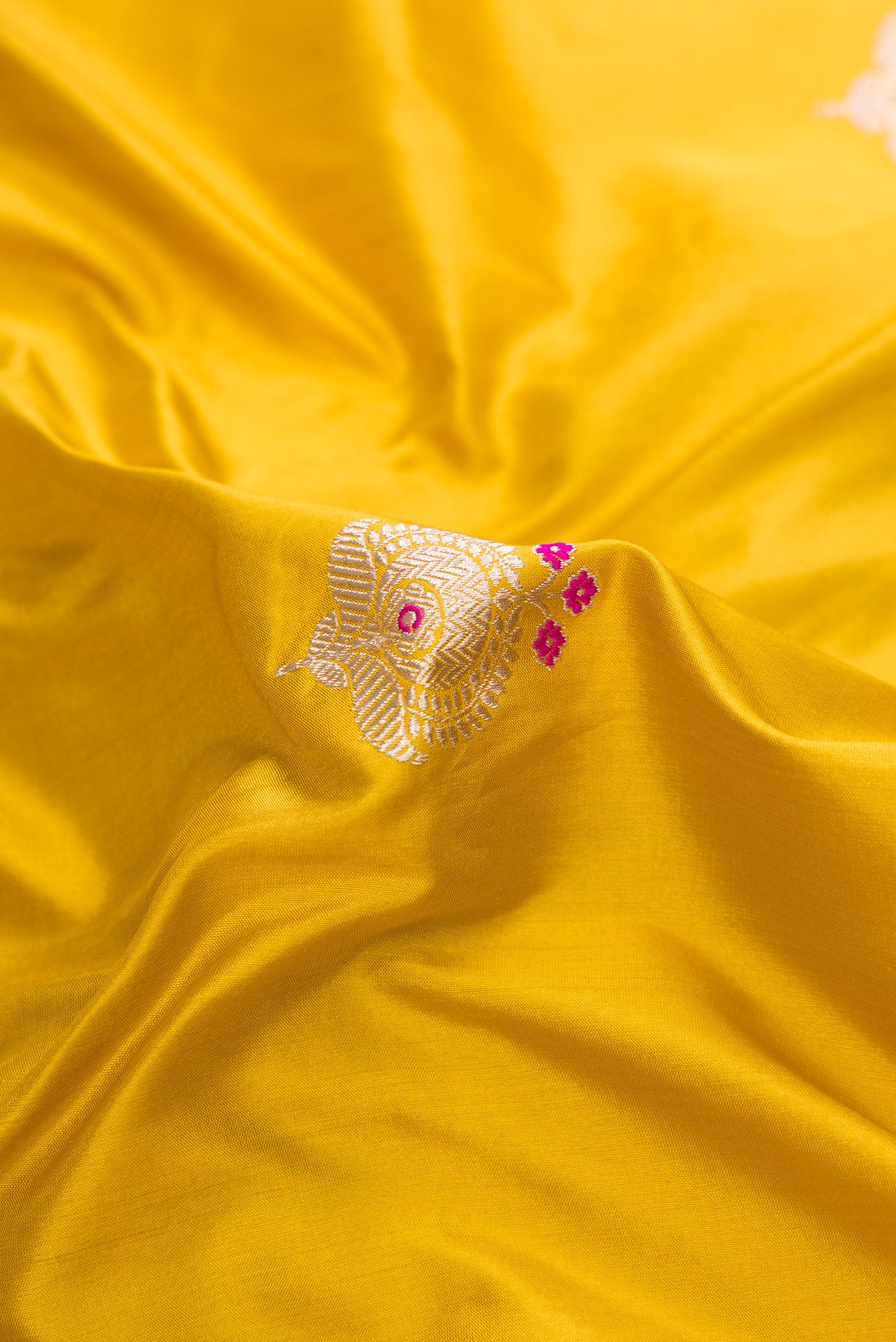 Close up of Mustard Dual Tone Banarasi Silk Saree with Zari And Thread Butta on the body and Fancy Border.  displaying folds