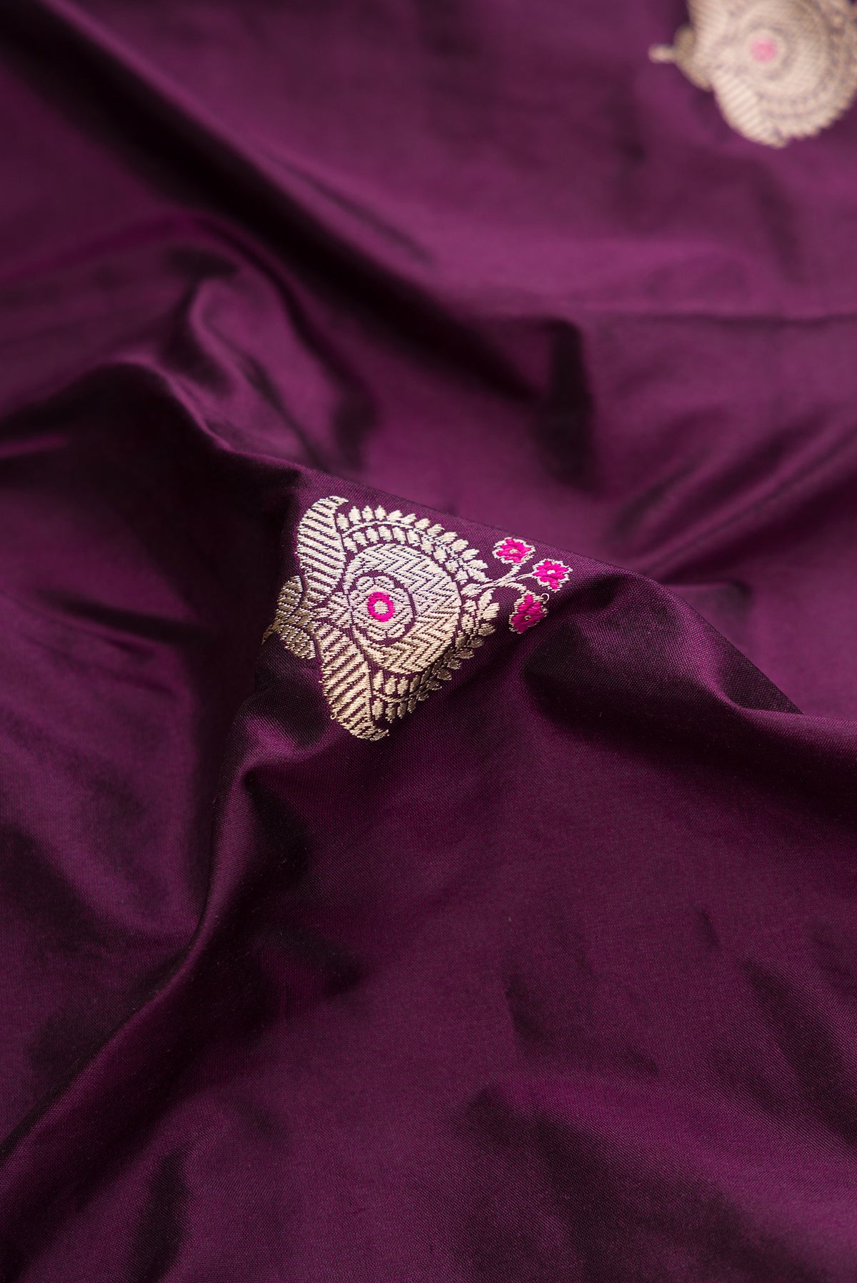 Close up of Burgundy Dual Tone Banarasi Silk Saree with Zari And Thread Butta on the body and Fancy Border.  displaying folds