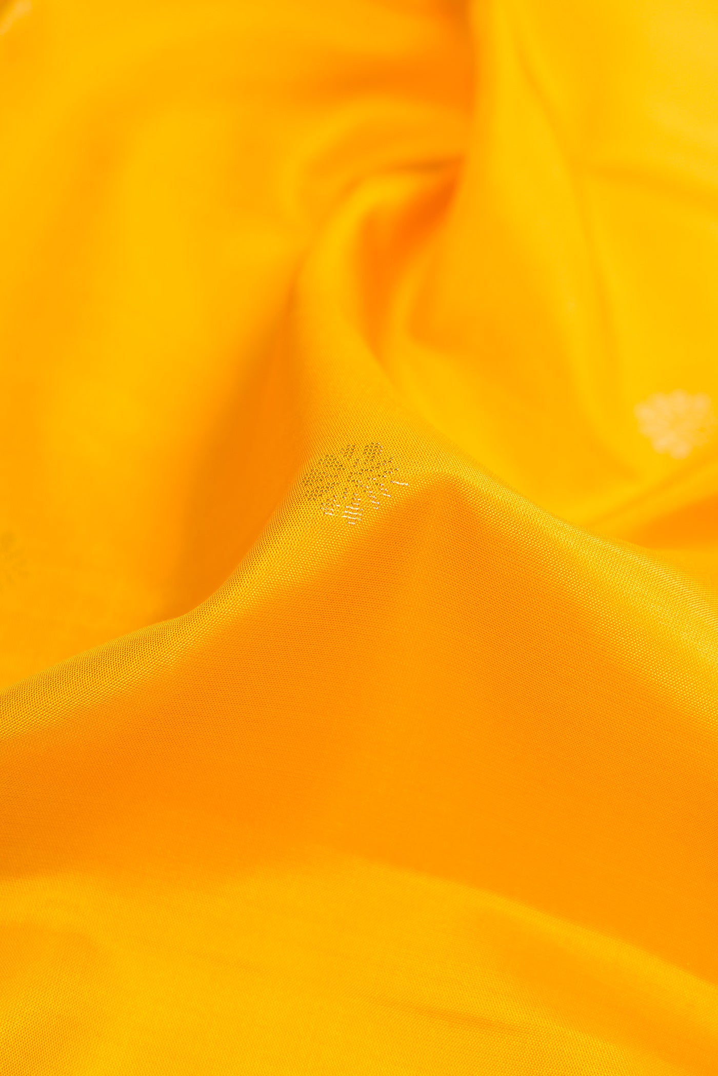 Close up of Yellow Soft Silk Saree with Zari Butta on the body and Fancy Border.  displaying folds