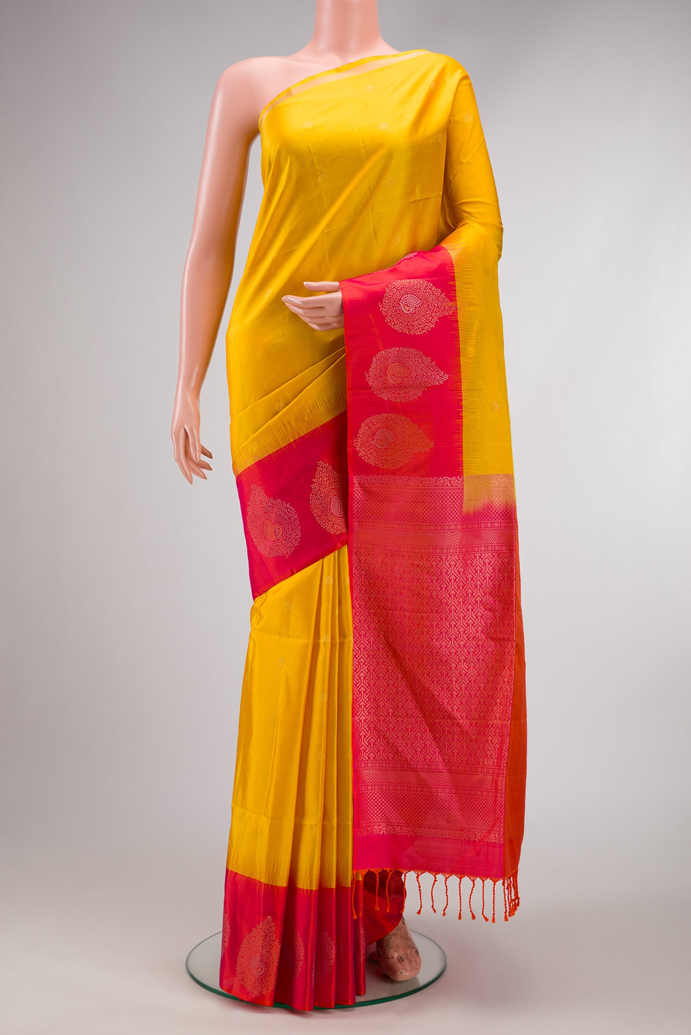 Yellow Soft Silk Saree with Zari Butta on the body and Fancy Border.  displayed on a mannequin