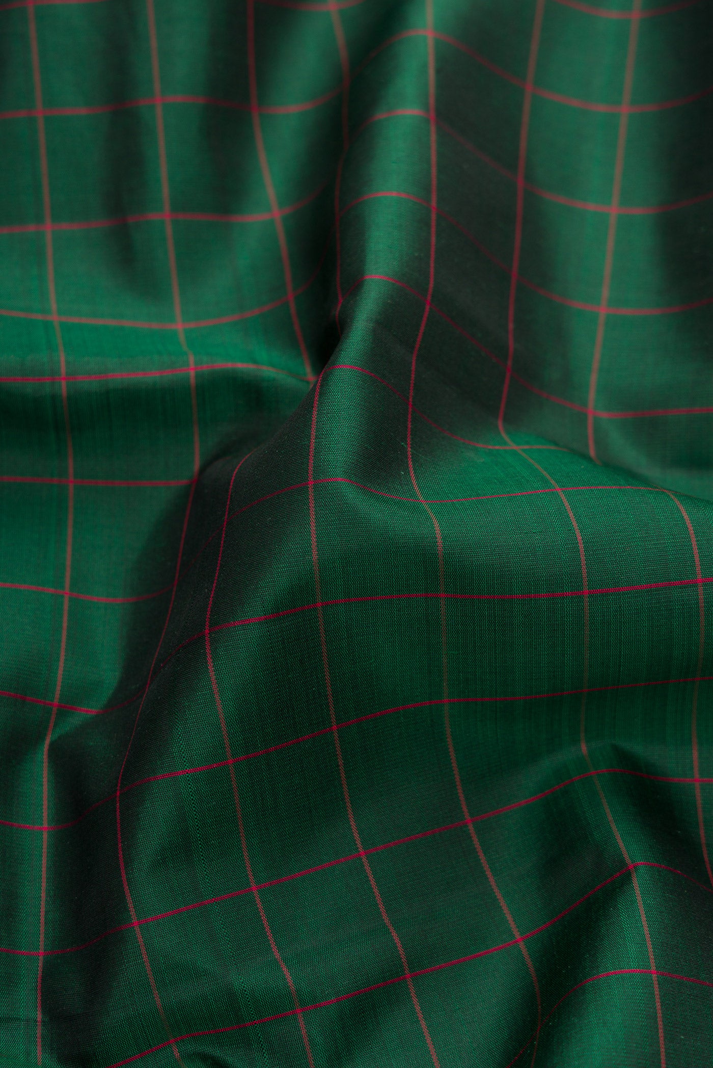 Close up of Green, Maroon & Burgundy Dual Tone Kanjivaram Silk Saree with Checked design on the body and Ganga Jamuna Border.  displaying folds