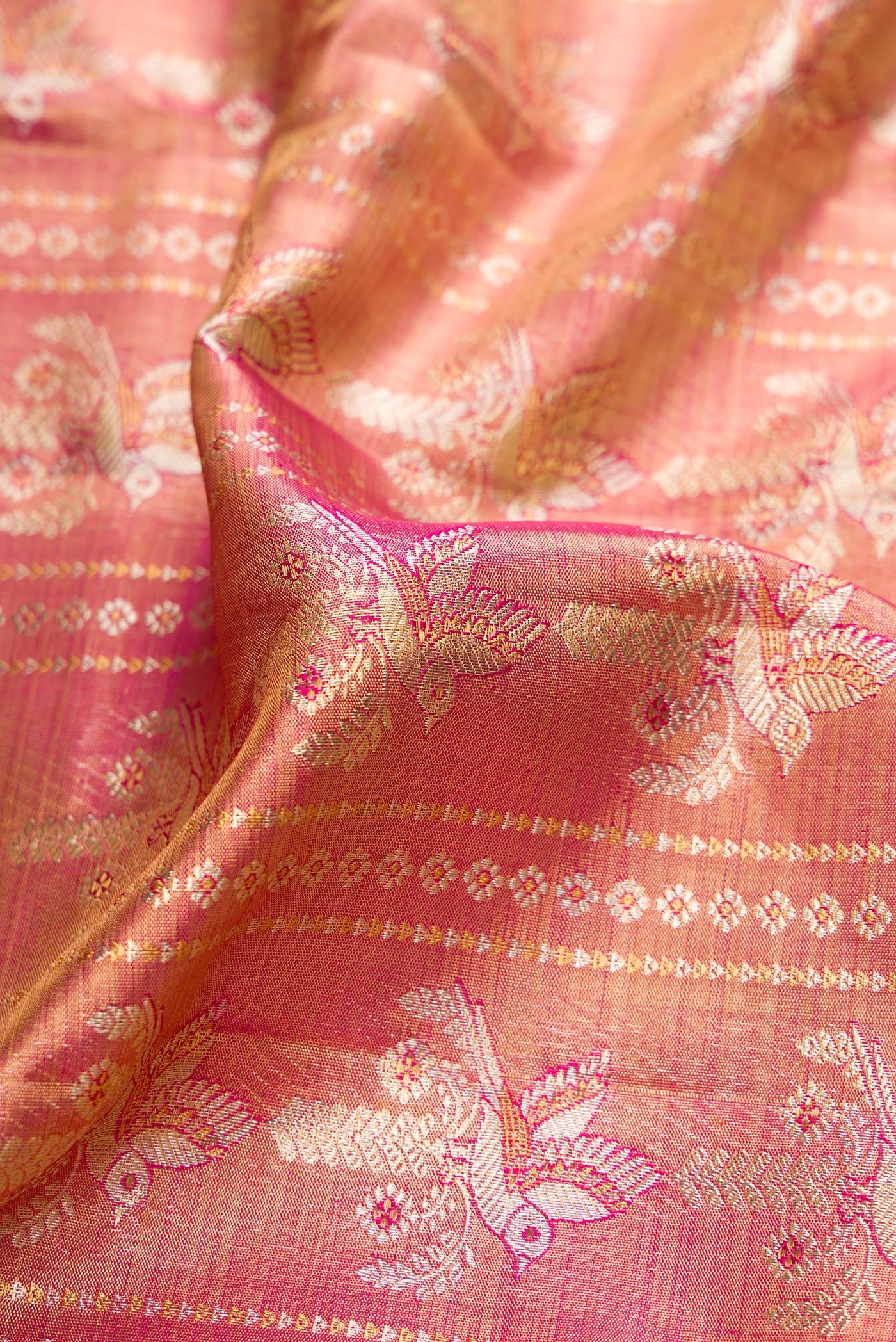 Close up of Magenta Dual Tone Kanjivaram Tissue Silk Saree with Zari Brocade on the body and Paithani Border.  displaying folds