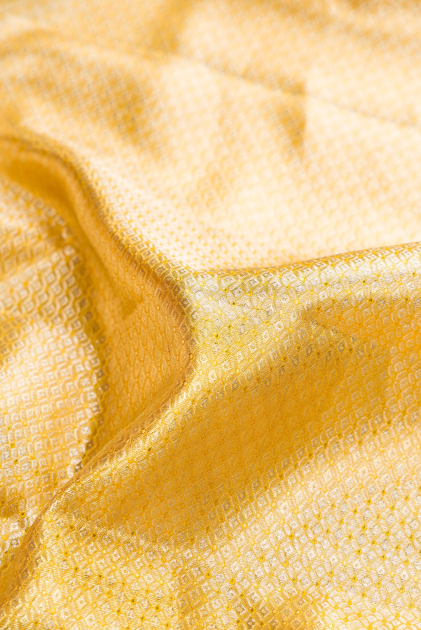 Close up of Pure Silk Pure Zari Yellow Dual Tone Kanjivaram Tissue Saree with Zari Brocade on the body and Fancy Border.  displaying folds