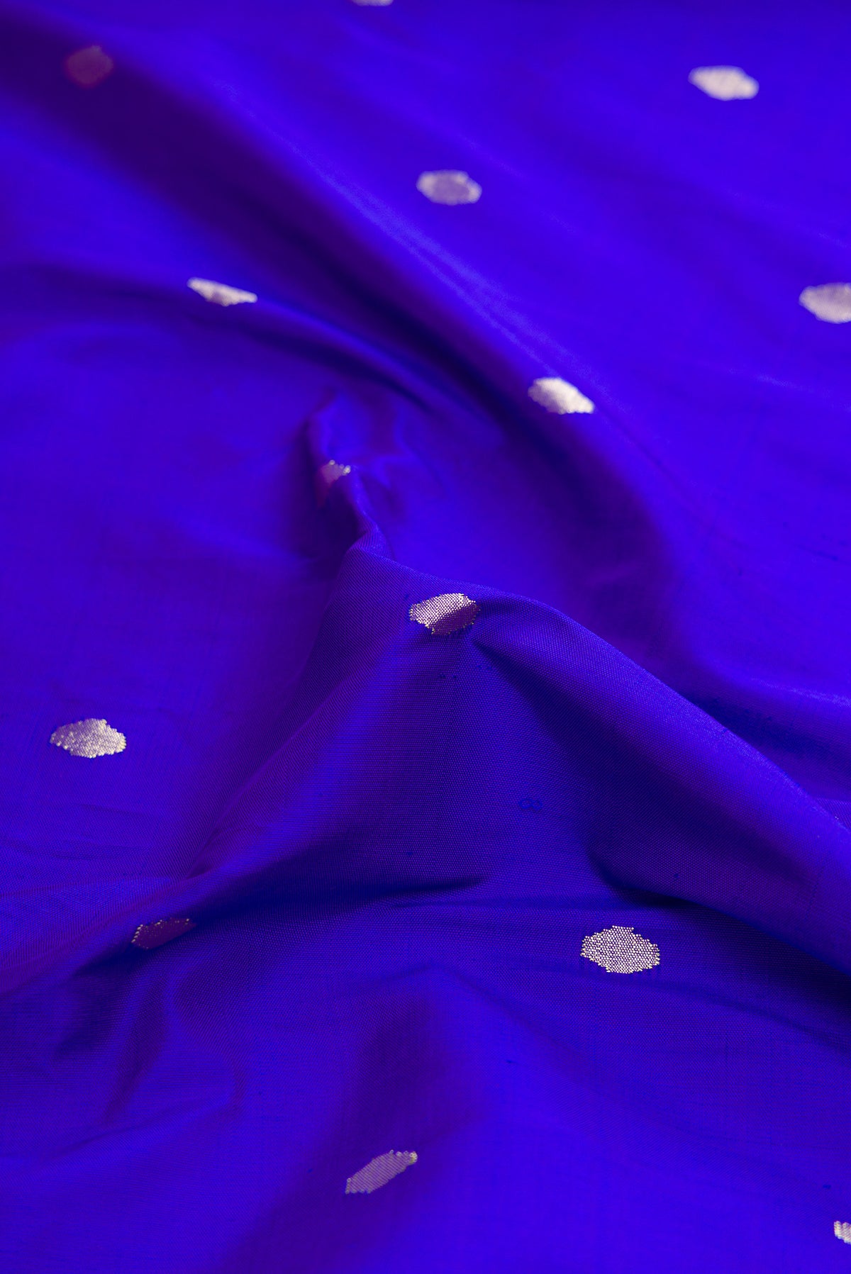 Close up of Pure Silk Pure Zari Royal Blue Dual Tone Paithani Saree with Zari Butta on the body and Paithani Border.  displaying folds