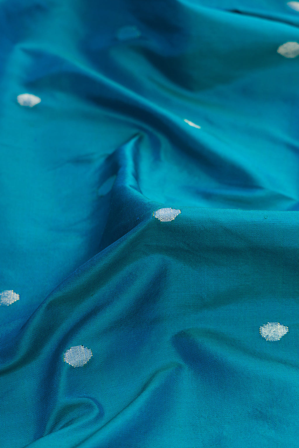Close up of Pure Silk Pure Zari Peacock Blue Dual Tone Paithani Saree with Zari Butta on the body and Paithani Border.  displaying folds