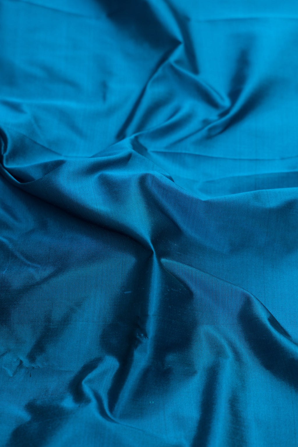 Close up of Peacock Blue Dual Tone Kanjivaram Silk Saree with Zari Butta on the body and Temple Border.  displaying folds