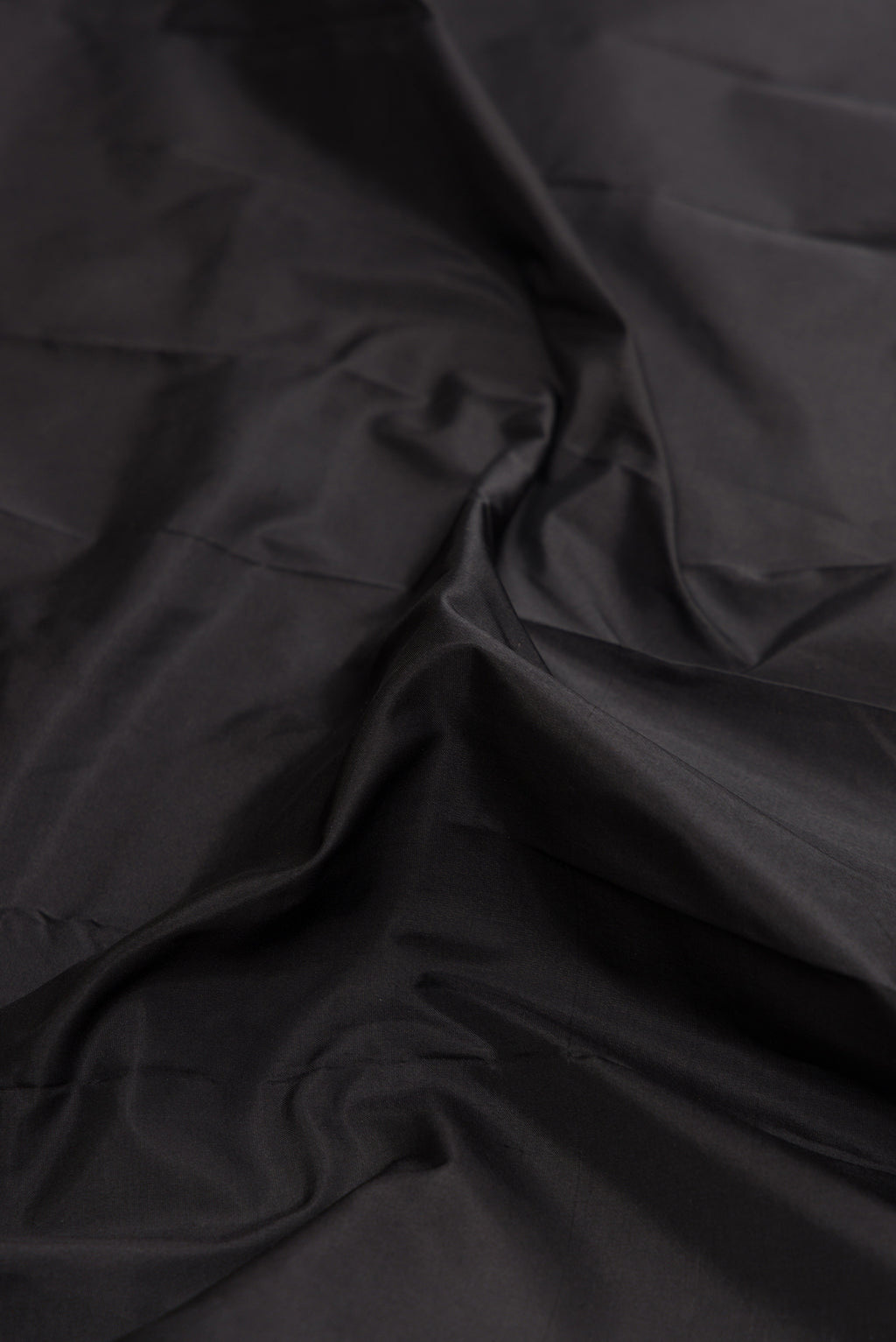 Close up of Black Dual Tone Kanjivaram Silk Saree with Plain Body and Zari Border.  displaying folds