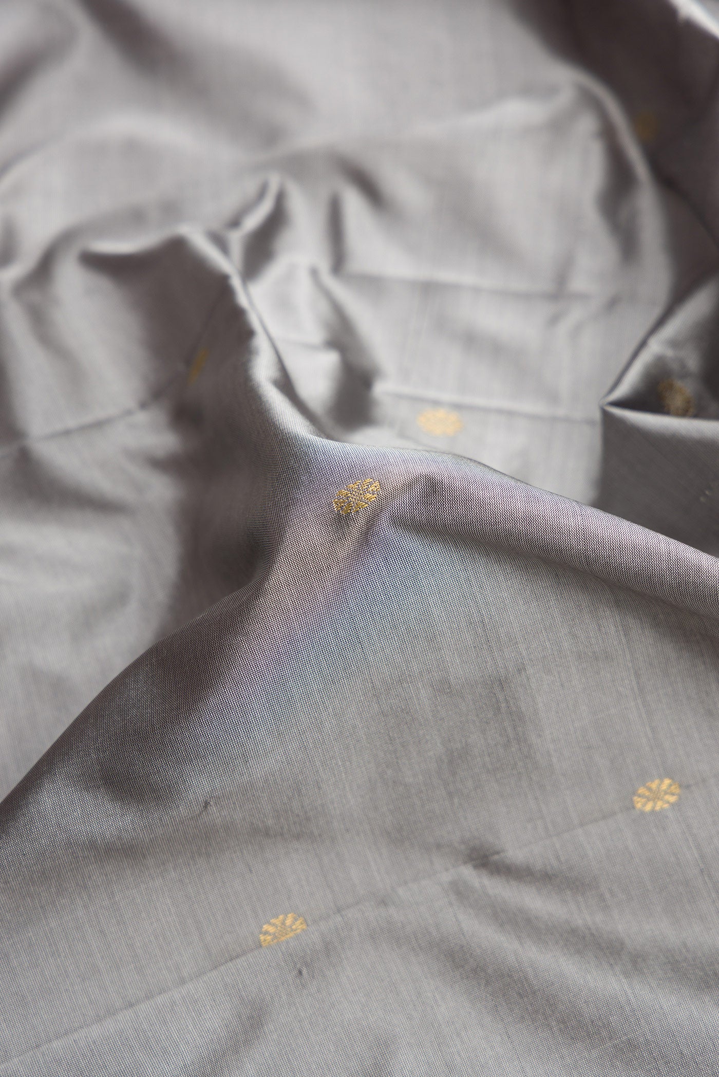 Close up of Grey Dual Tone Kanchipuram Silk Saree with Zari Butta on the body and Temple Border.  displaying folds