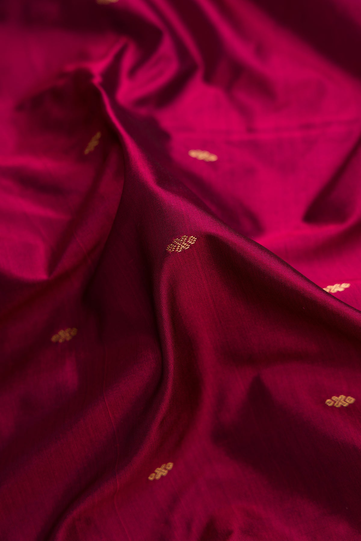 Close up of Burgundy Dual Tone Kanchipuram Silk Saree with Zari Butta on the body and Temple Border.  displaying folds