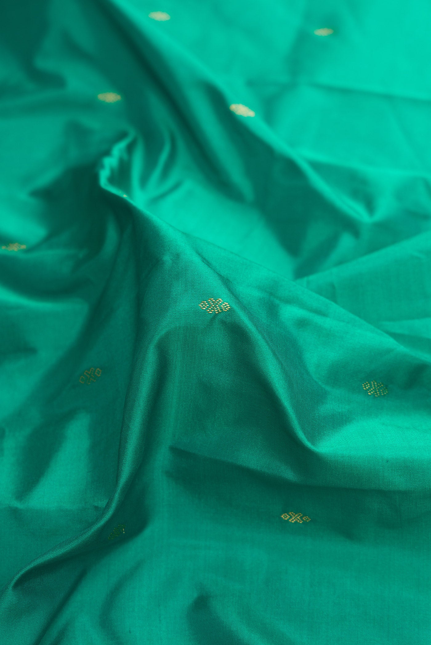 Close up of Green Dual Tone Kanchipuram Silk Saree with Zari Butta on the body and Temple Border.  displaying folds