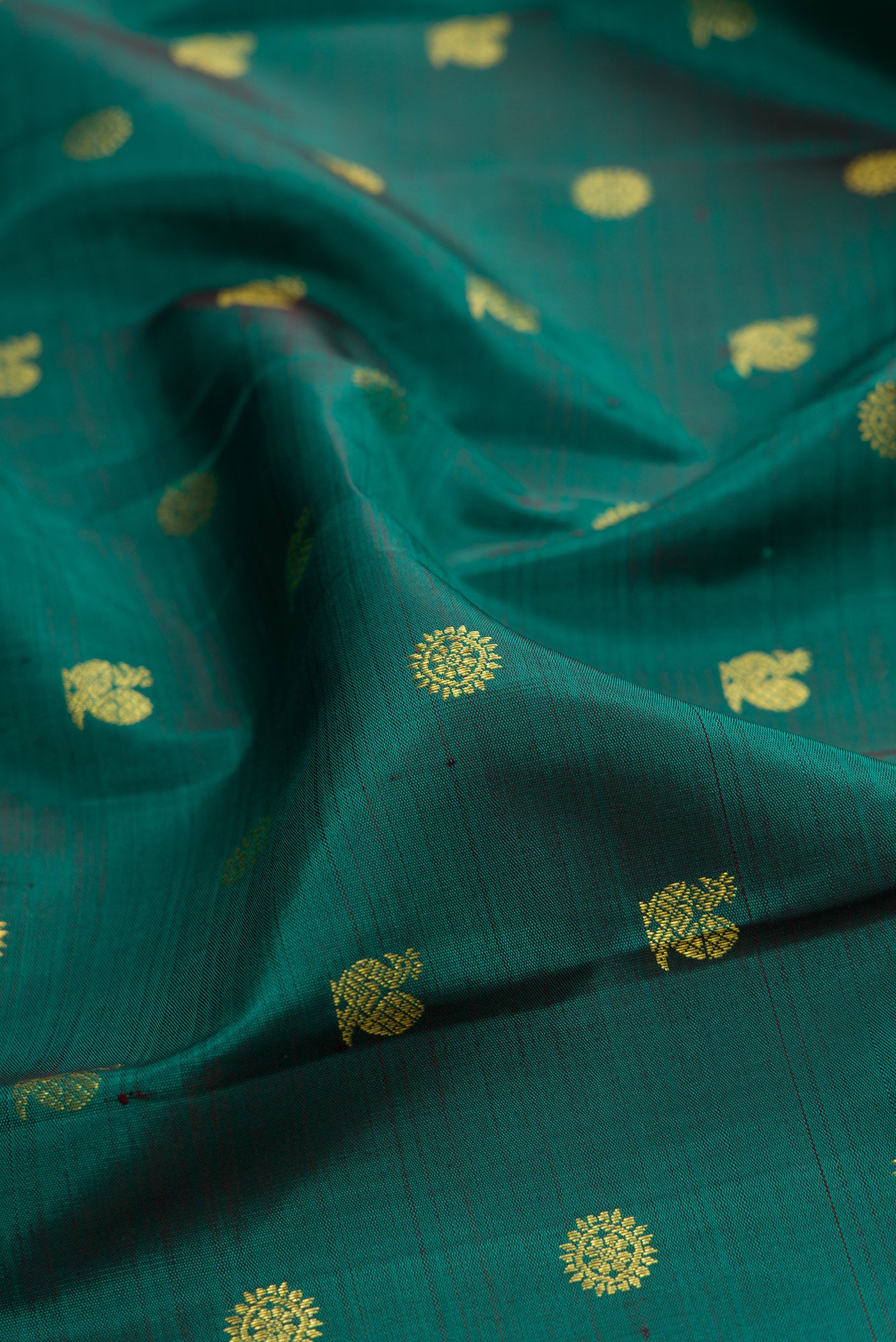 Close up of Green Kanjivaram Silk Saree with Zari Butta on the body and Zari Border.  displaying folds