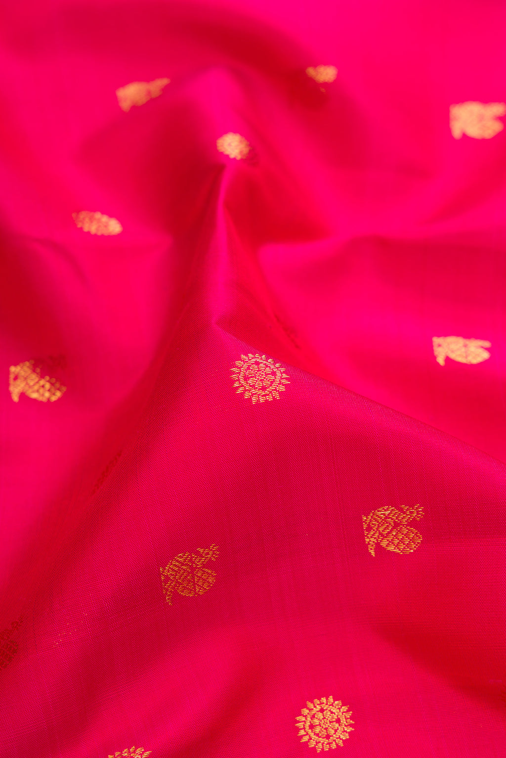 Close up of Dark Pink Kanjivaram Silk Saree with Zari Butta on the body and Zari Border.  displaying folds