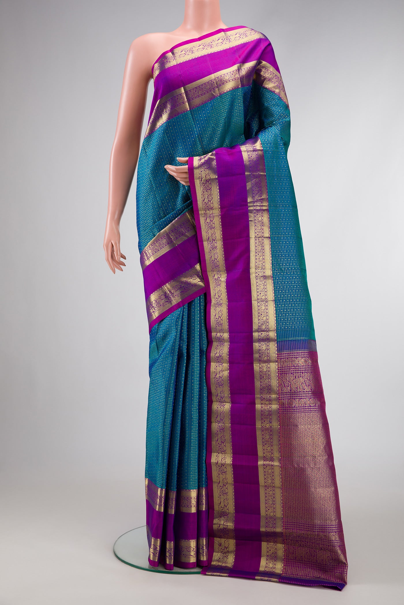 Peacock Blue Dual Tone Kanchipuram Silk Saree with Checked design on the body and Zari Border.  displayed on a mannequin