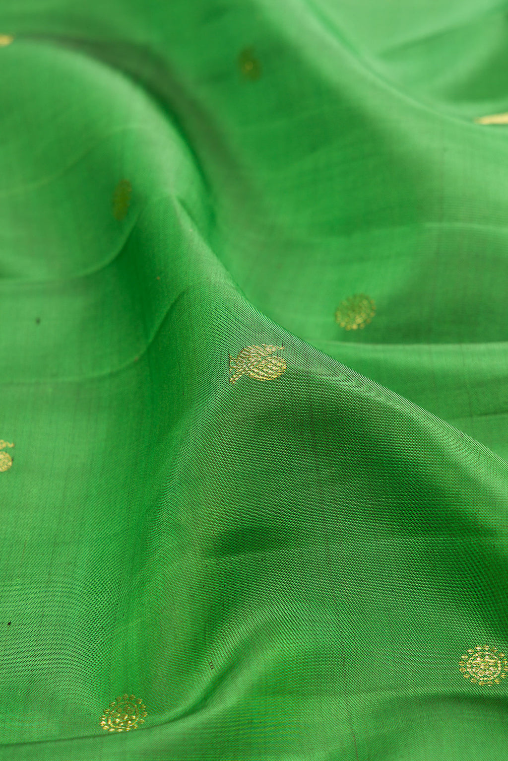 Close up of Green Kanchipuram Silk Saree with Zari Butta on the body and Zari Border.  displaying folds