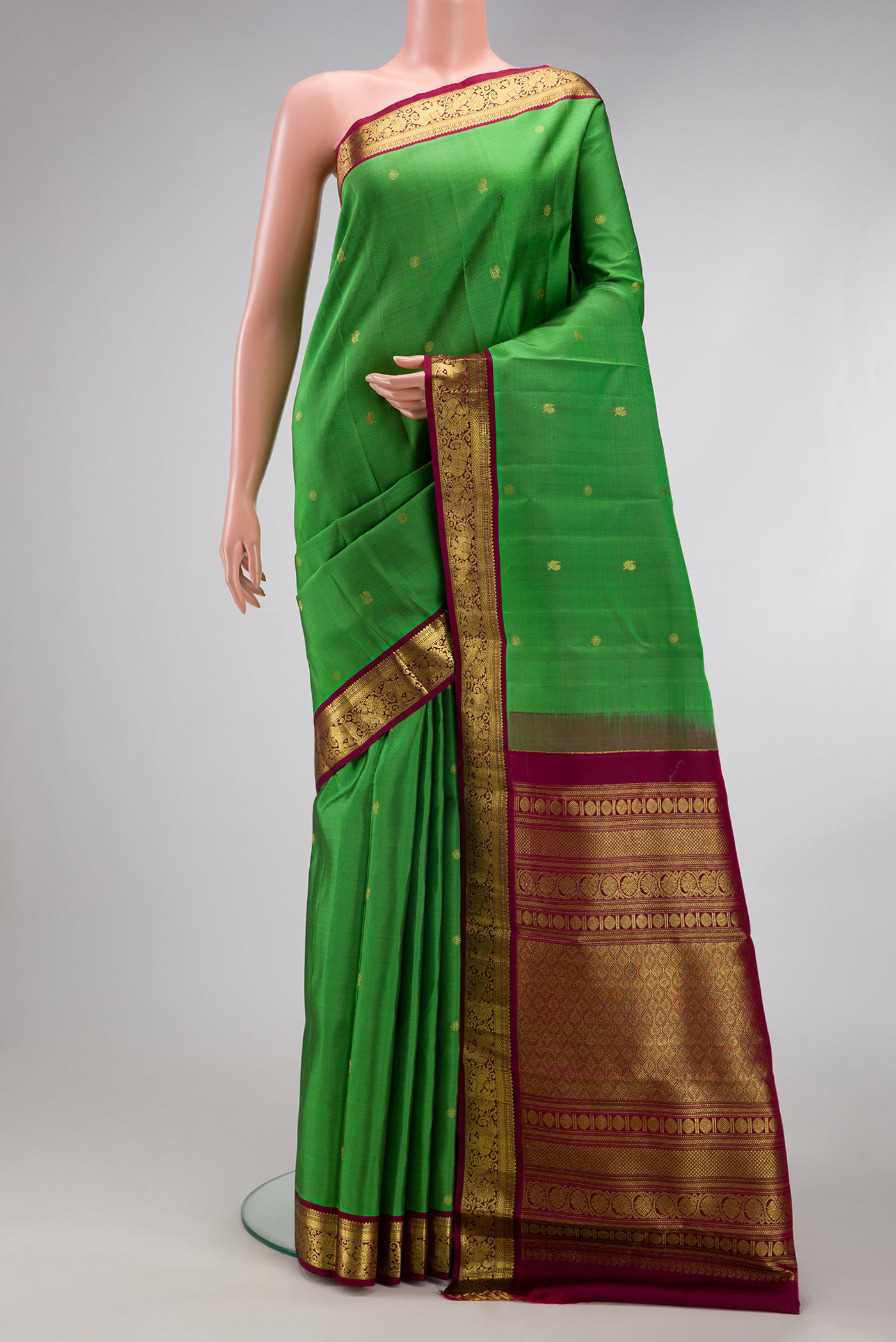 Green Kanchipuram Silk Saree with Zari Butta on the body and Zari Border.  displayed on a mannequin