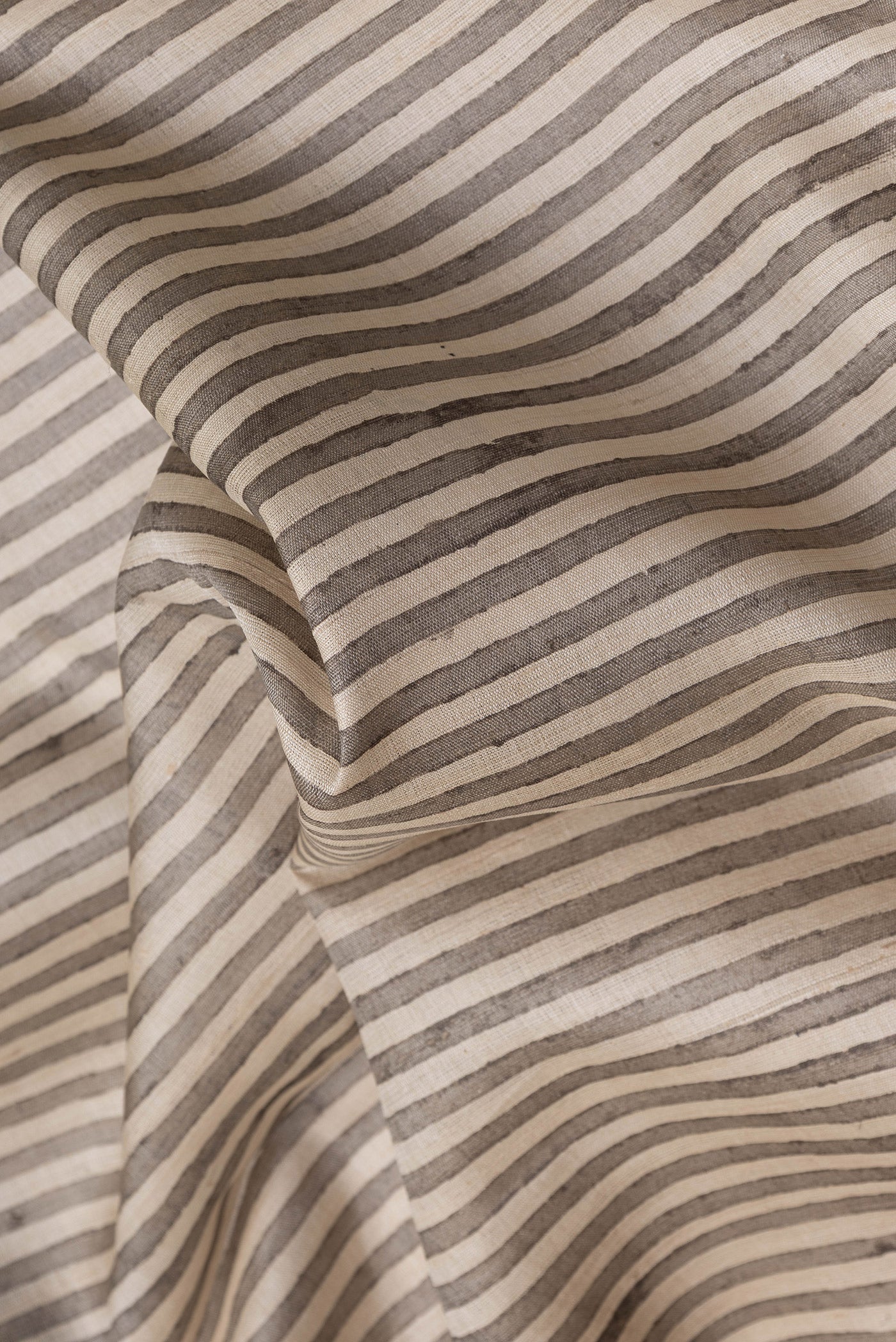 Close up of Beige Dual Tone Tussar Silk Saree with Stripes on the body and Embroidery Border.  displaying folds