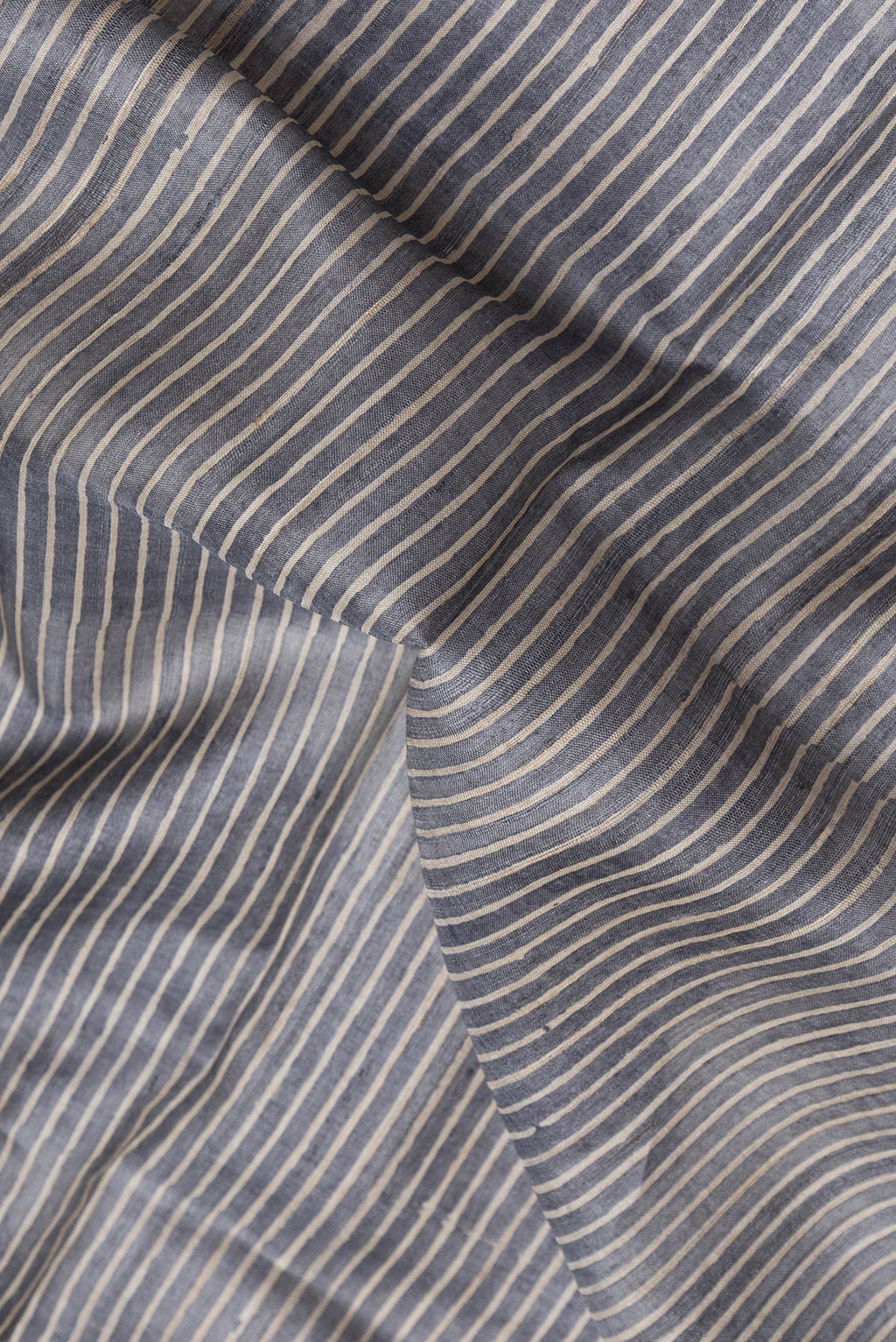 Close up of Grey Dual Tone Tussar Silk Saree with Stripes on the body and Embroidery Border.  displaying folds