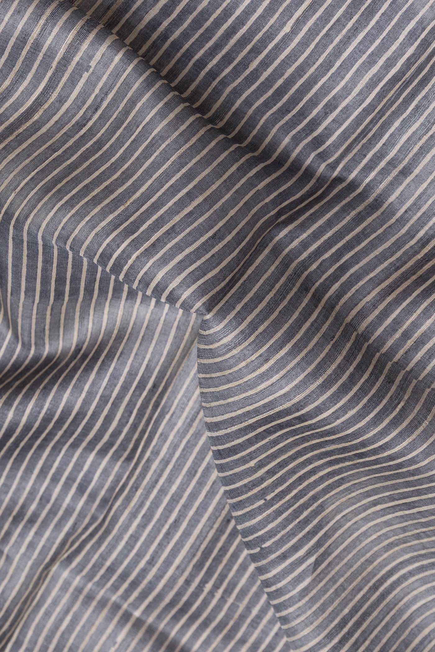 Close up of Grey Dual Tone Tussar Silk Saree with Stripes on the body and Embroidery Border.  displaying folds