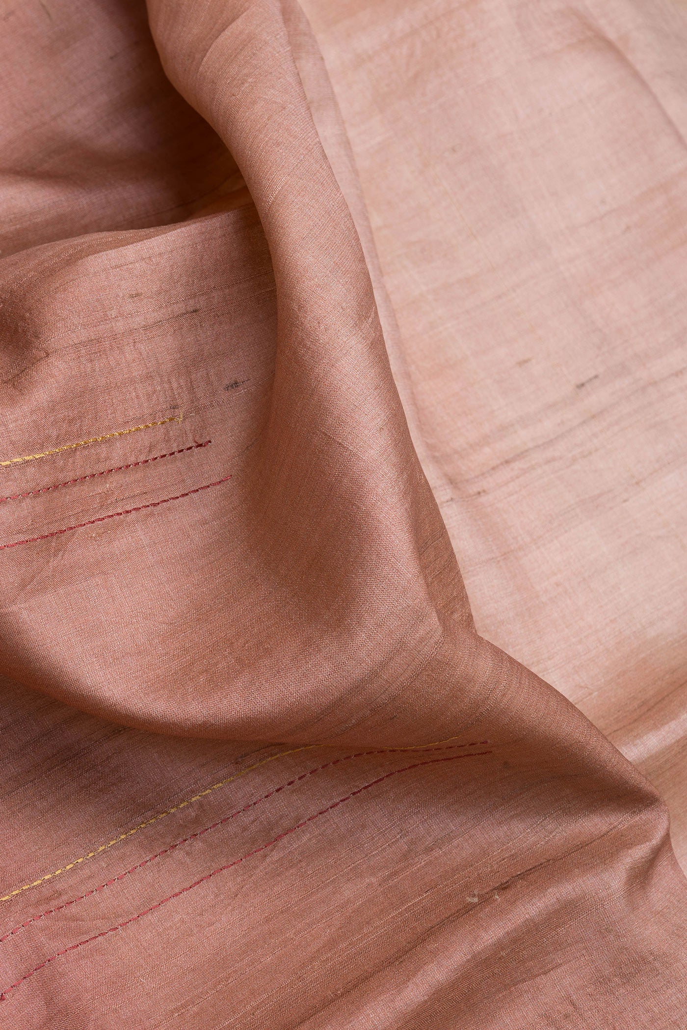 Close up of Rose Gold Dual Tone Tussar Silk Saree with Embroidery on the body and Fancy Border.  displaying folds