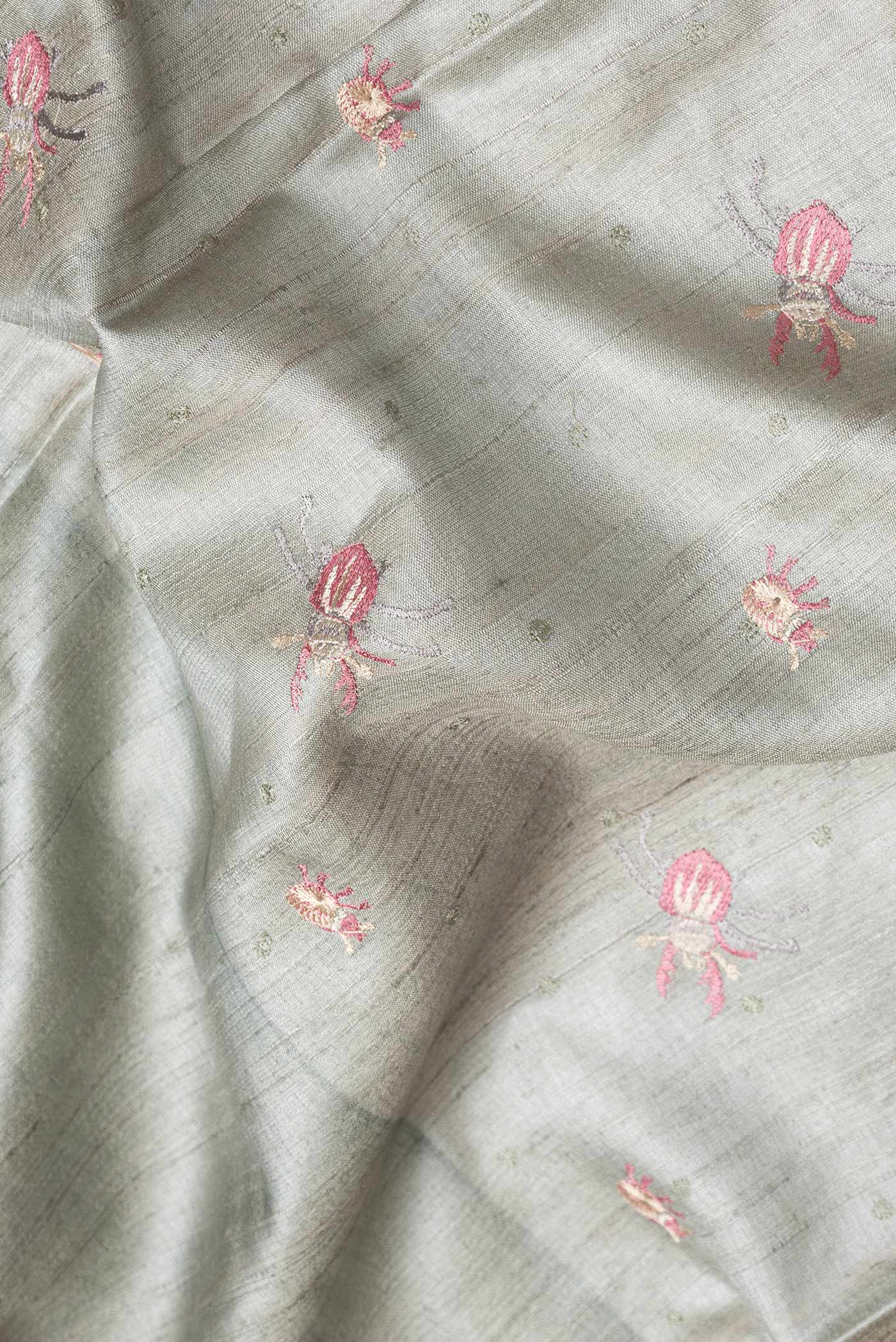 Close up of Grey Dual Tone Tussar Silk Saree with Thread Butta on the body and Embroidery Border.  displaying folds