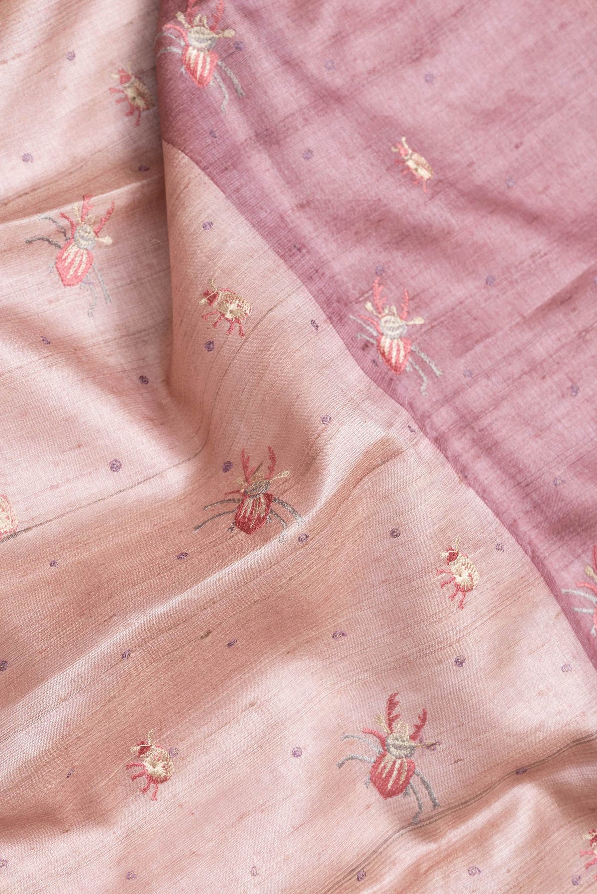 Close up of Pink Dual Tone Tussar Silk Saree with Thread Butta on the body and Embroidery Border.  displaying folds