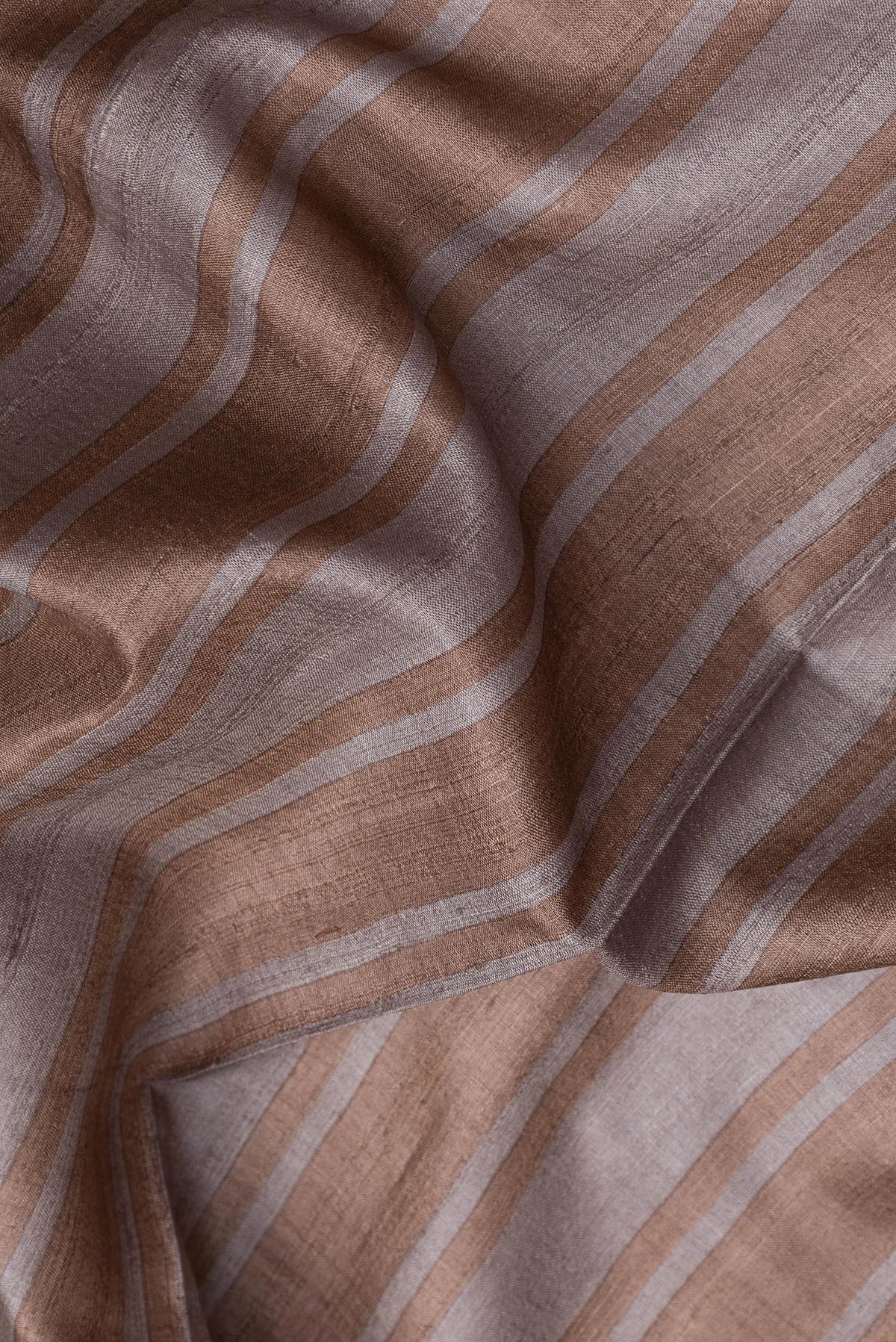 Close up of Grey Dual Tone Tussar Silk Saree with Stripes on the body and Embroidery Border.  displaying folds